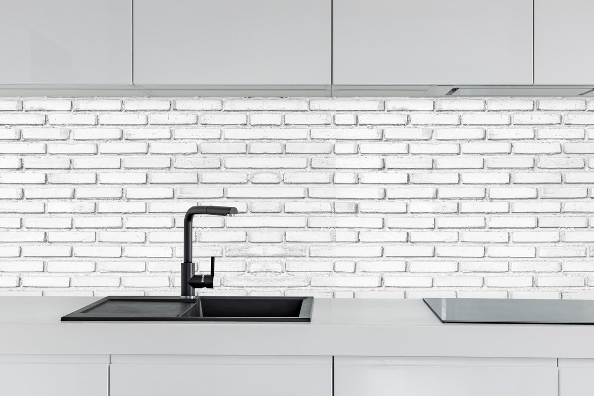 Küche - Weiße Backsteinmauer hinter weißen Hochglanz-Küchenregalen und schwarzem Wasserhahn