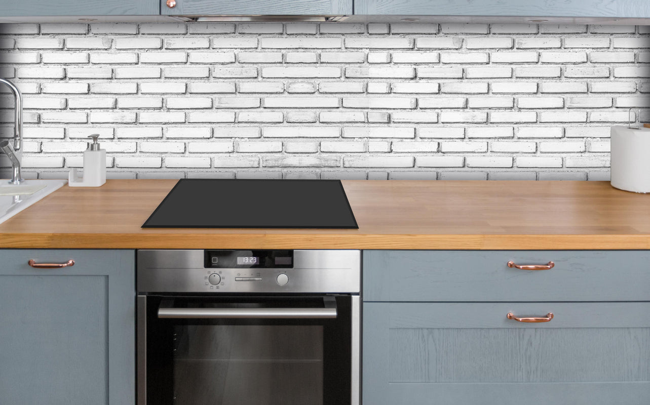 Küche - Weiße Backsteinmauer über polierter Holzarbeitsplatte mit Cerankochfeld