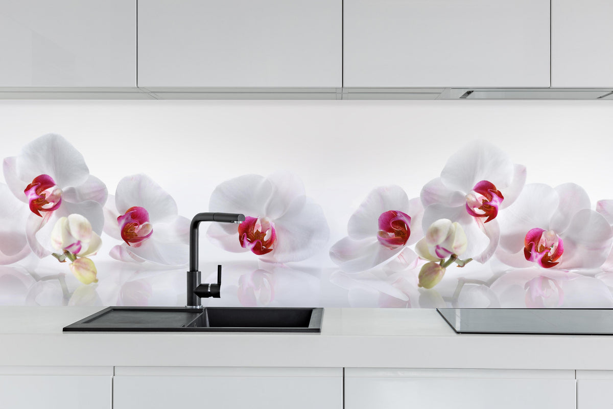 Küche - Weiße Orchideen hinter weißen Hochglanz-Küchenregalen und schwarzem Wasserhahn