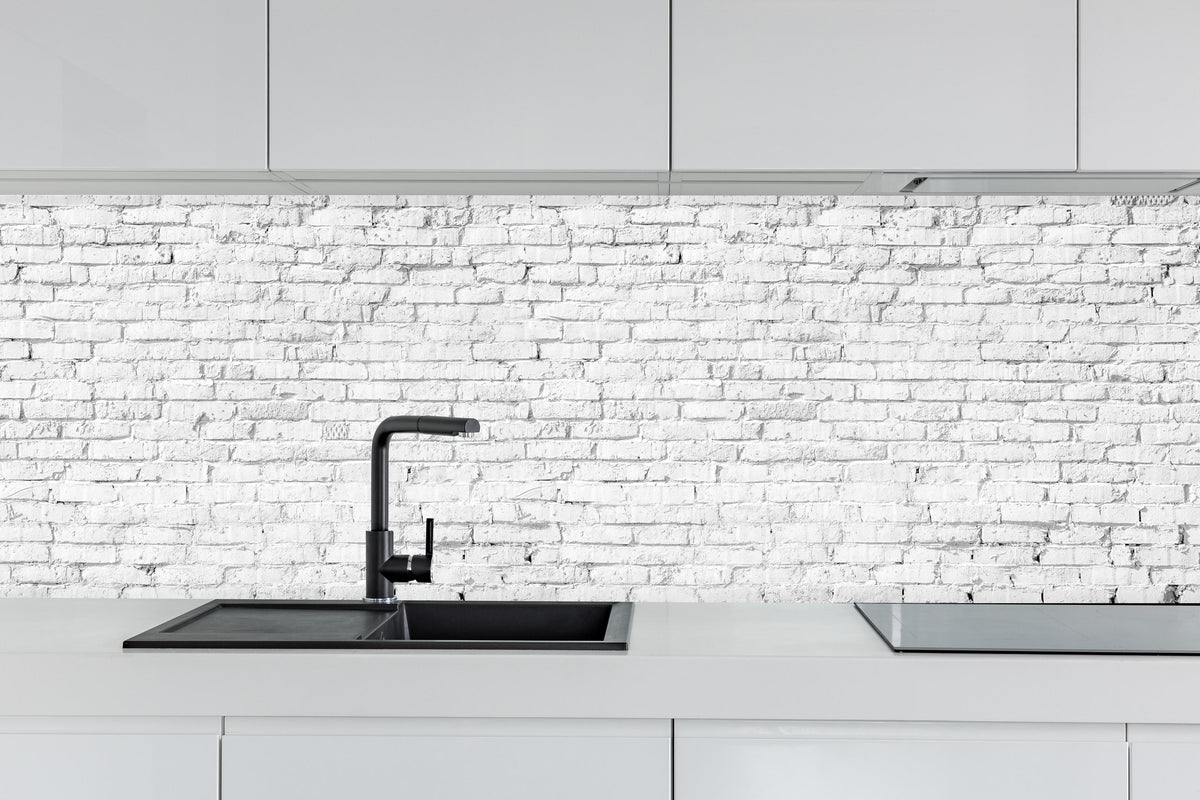 Küche - Weiße Ziegelwand - Steinmauer hinter weißen Hochglanz-Küchenregalen und schwarzem Wasserhahn