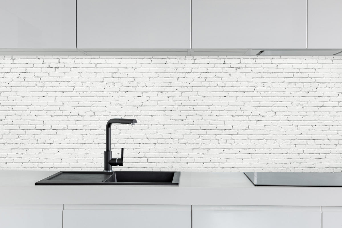 Küche - Weiße lange Backsteinfassade hinter weißen Hochglanz-Küchenregalen und schwarzem Wasserhahn