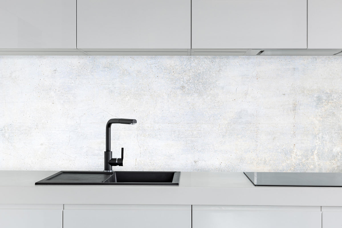 Küche - Weiße verwitterte Betonwand hinter weißen Hochglanz-Küchenregalen und schwarzem Wasserhahn