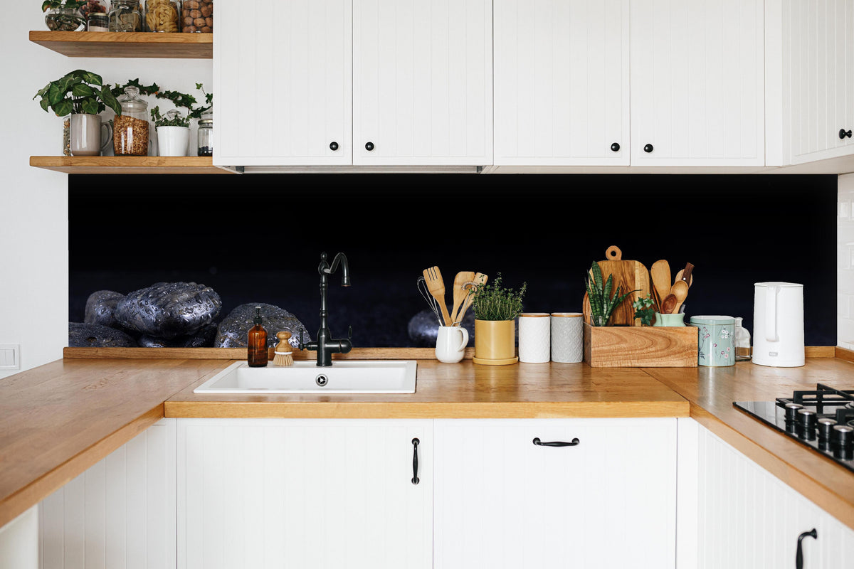 Küche - Zen - Schwarze Steine in weißer Küche hinter Gewürzen und Kochlöffeln aus Holz