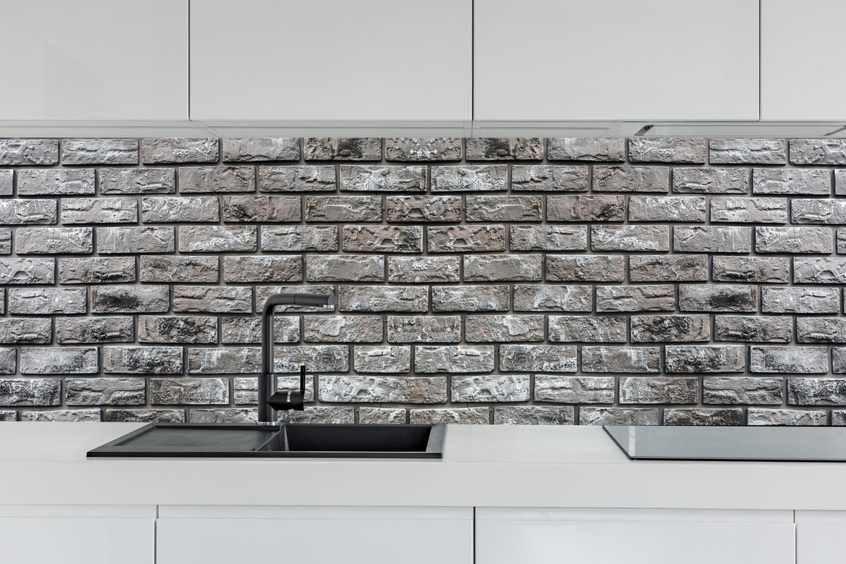Küche - Ziegelmauer aus dekorativem grauem Stein hinter weißen Hochglanz-Küchenregalen und schwarzem Wasserhahn