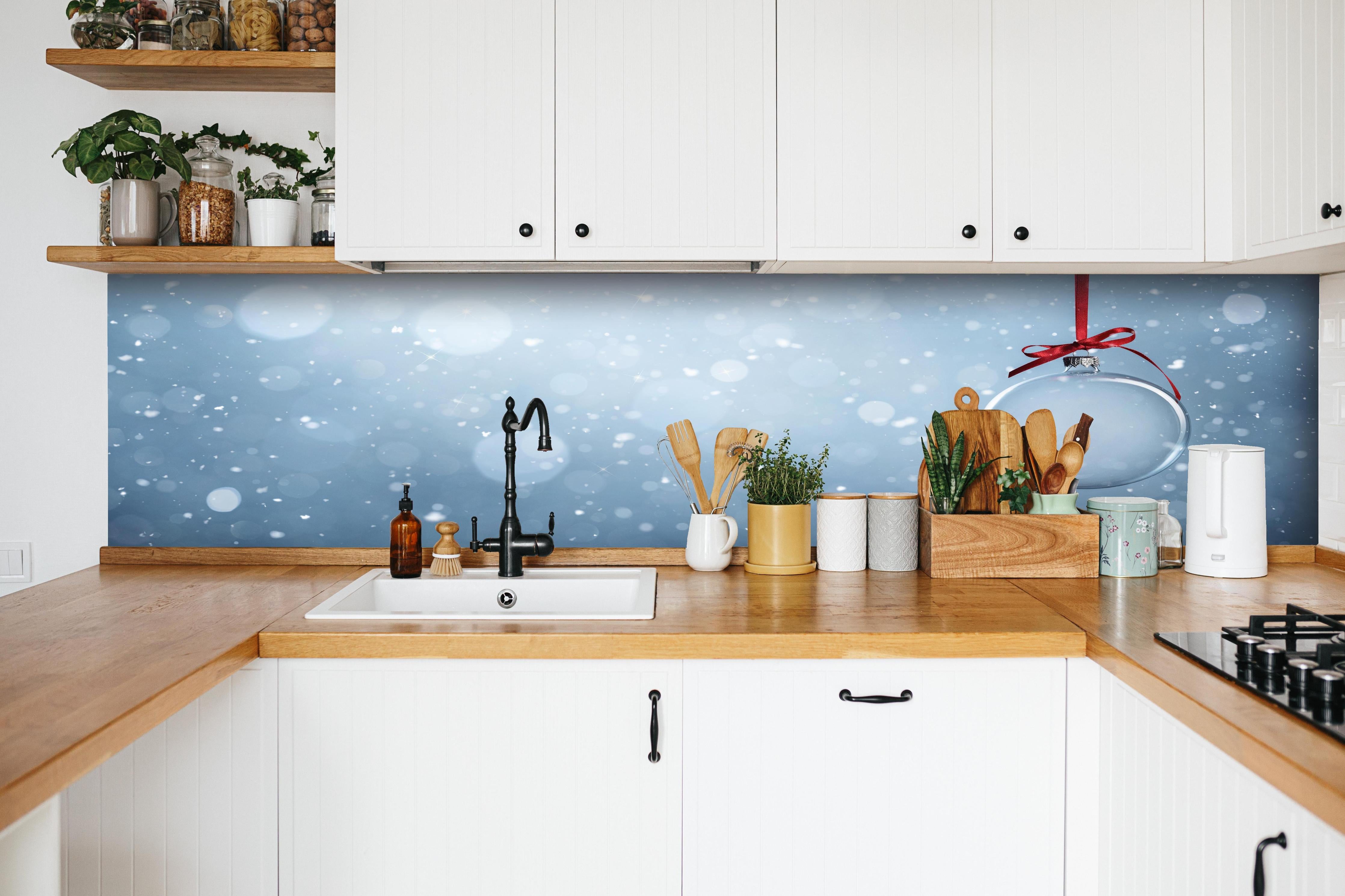 Küche - Leere Weihnachtskugel hinter weißen Hochglanz-Küchenregalen und schwarzem Wasserhahn