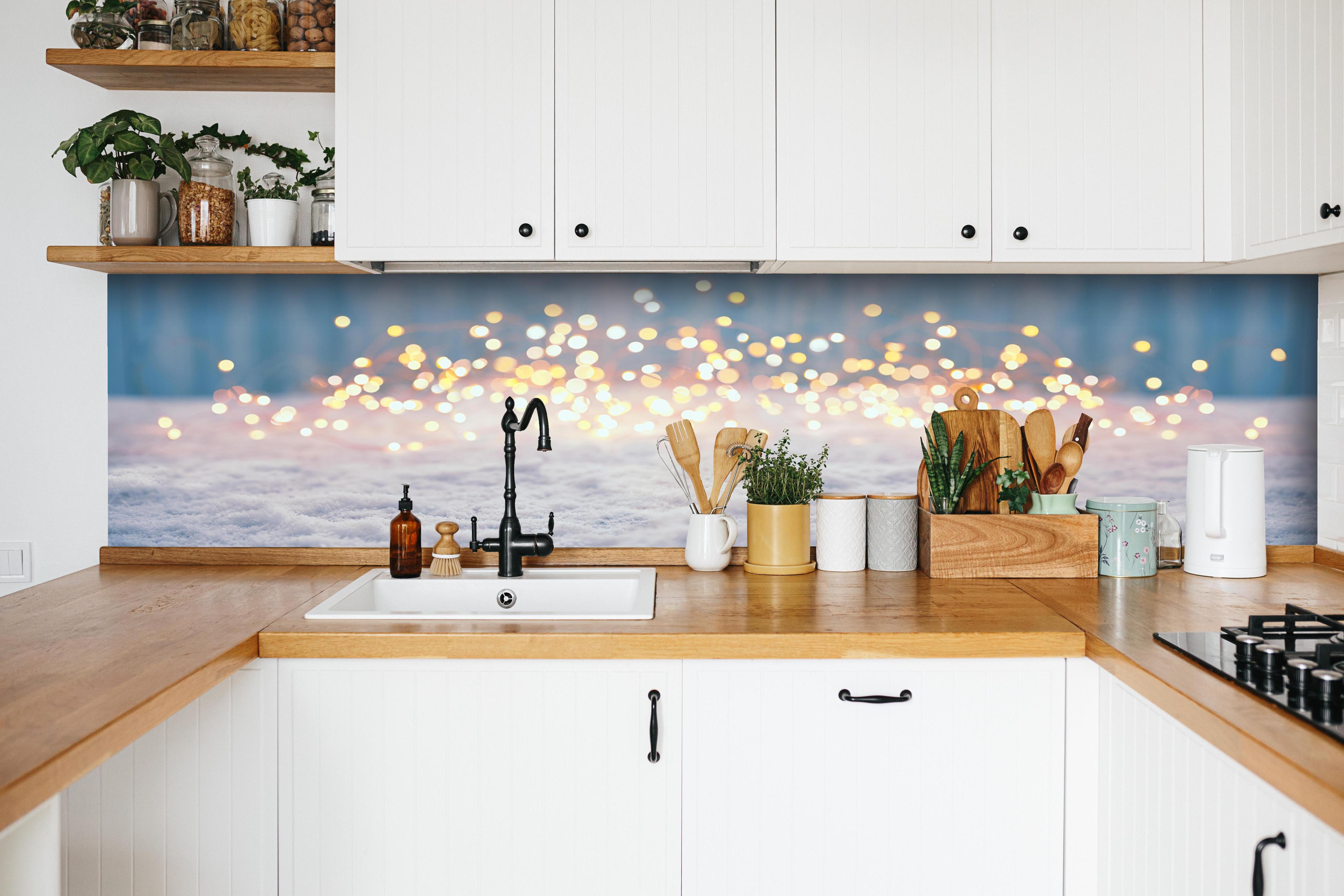 Küche - Magische Winterlandschaft mit goldenem Bokeh hinter weißen Hochglanz-Küchenregalen und schwarzem Wasserhahn