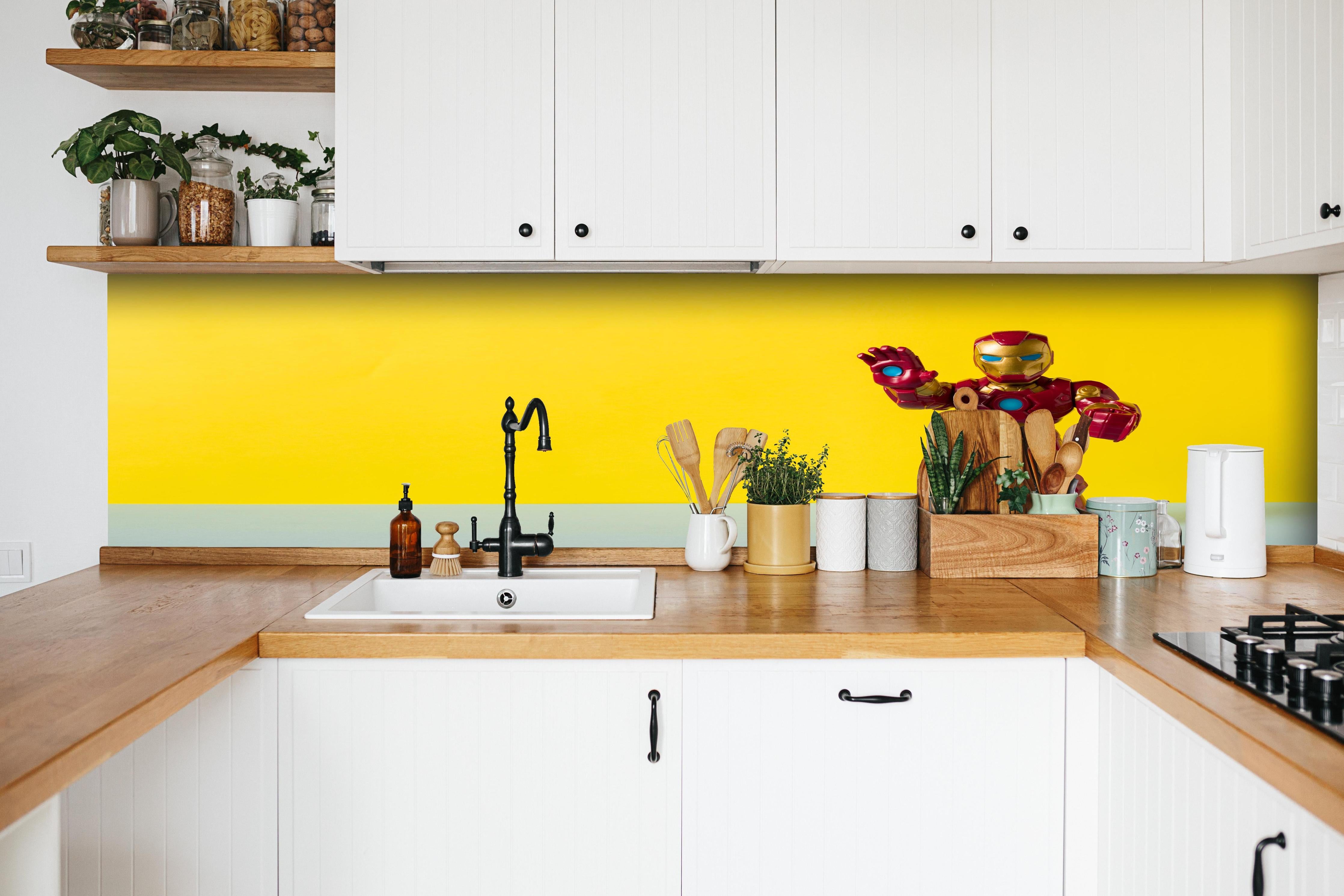 Küche - Marvel Iron Man Sammelfigur auf Gelb hinter weißen Hochglanz-Küchenregalen und schwarzem Wasserhahn