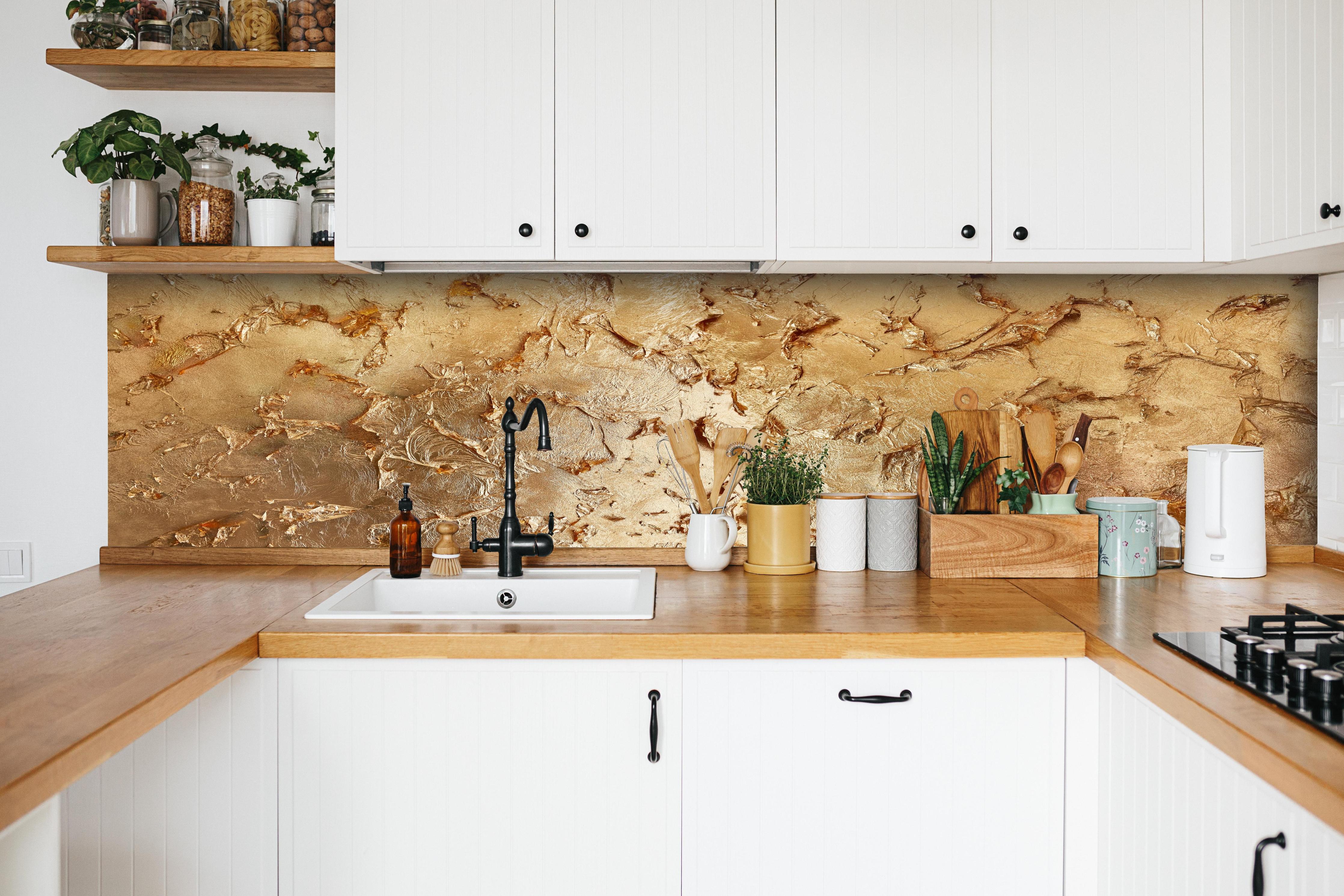 Küche - Muster einer vergoldeten Wand hinter weißen Hochglanz-Küchenregalen und schwarzem Wasserhahn