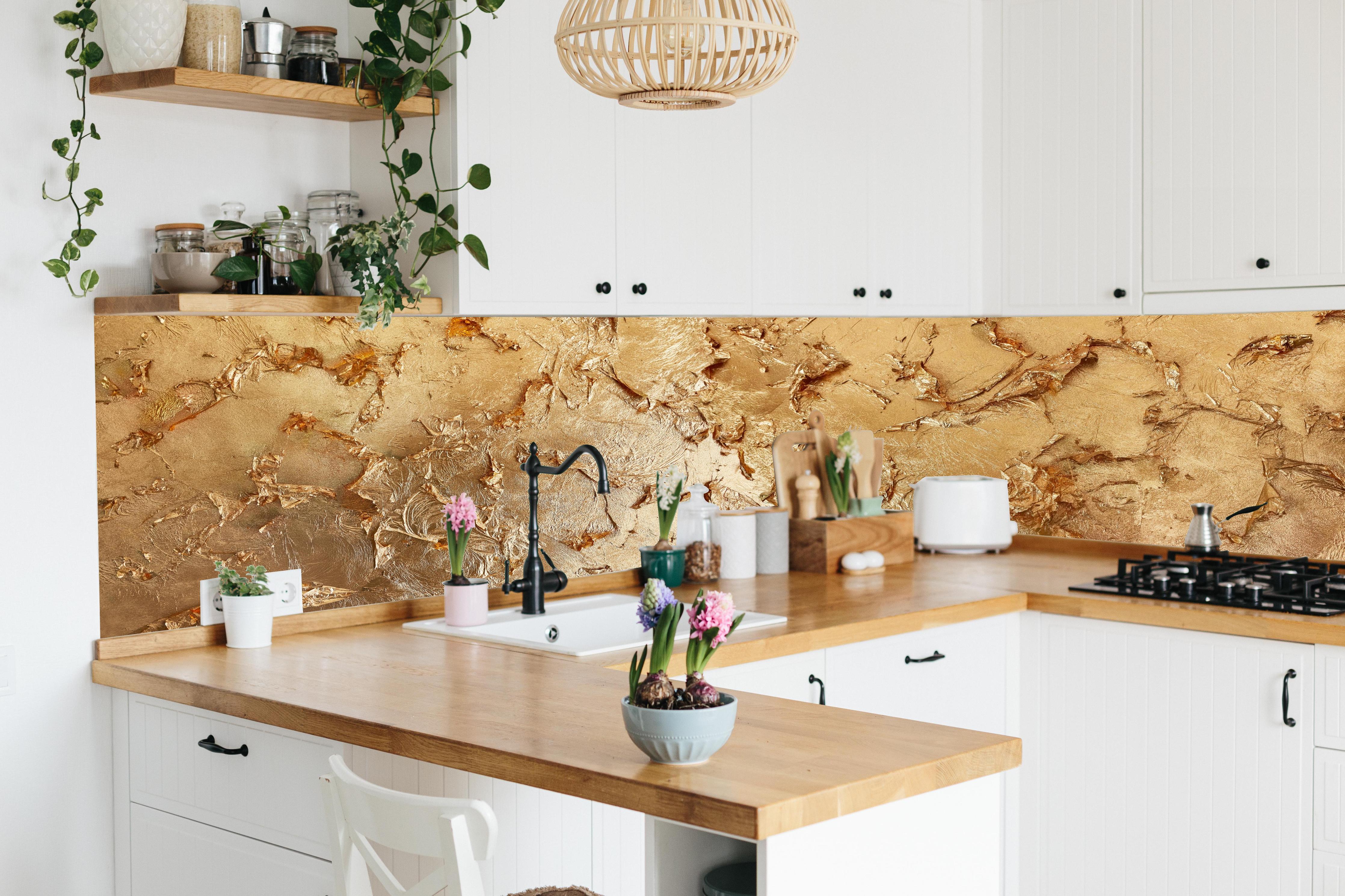 Küche - Muster einer vergoldeten Wand hinter weißen Hochglanz-Küchenregalen und schwarzem Wasserhahn