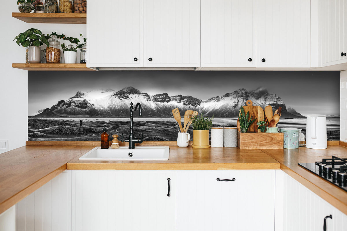 Küche - Panorama - Bergkette Vestrahorn hinter weißen Hochglanz-Küchenregalen und schwarzem Wasserhahn
