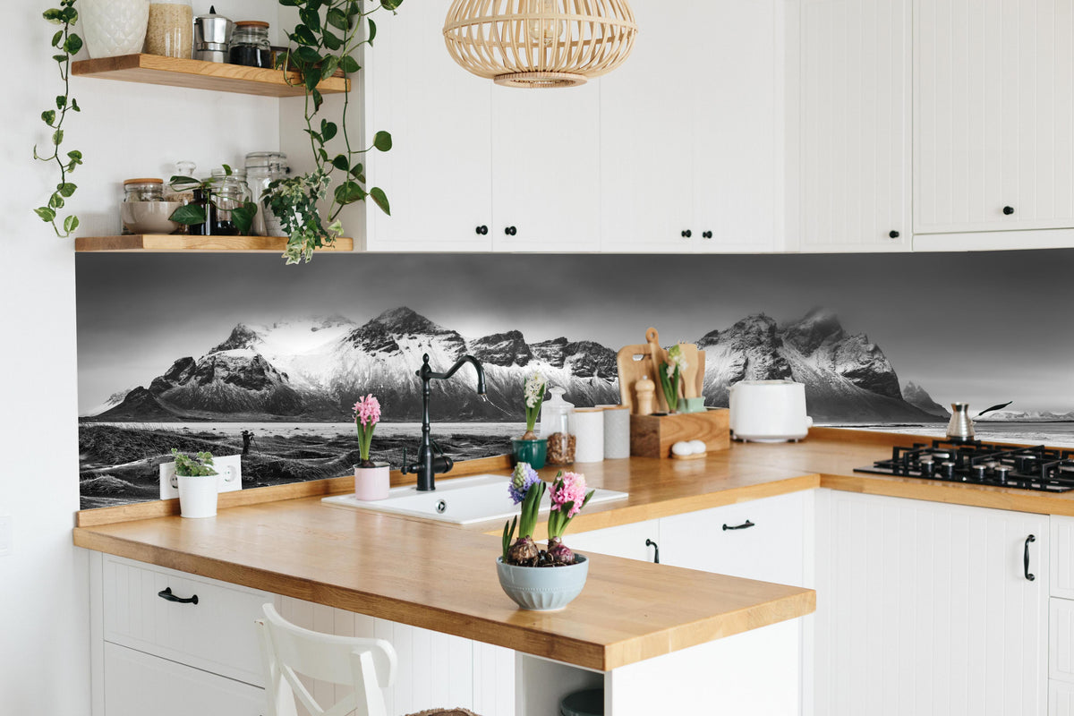 Küche - Panorama - Bergkette Vestrahorn hinter weißen Hochglanz-Küchenregalen und schwarzem Wasserhahn