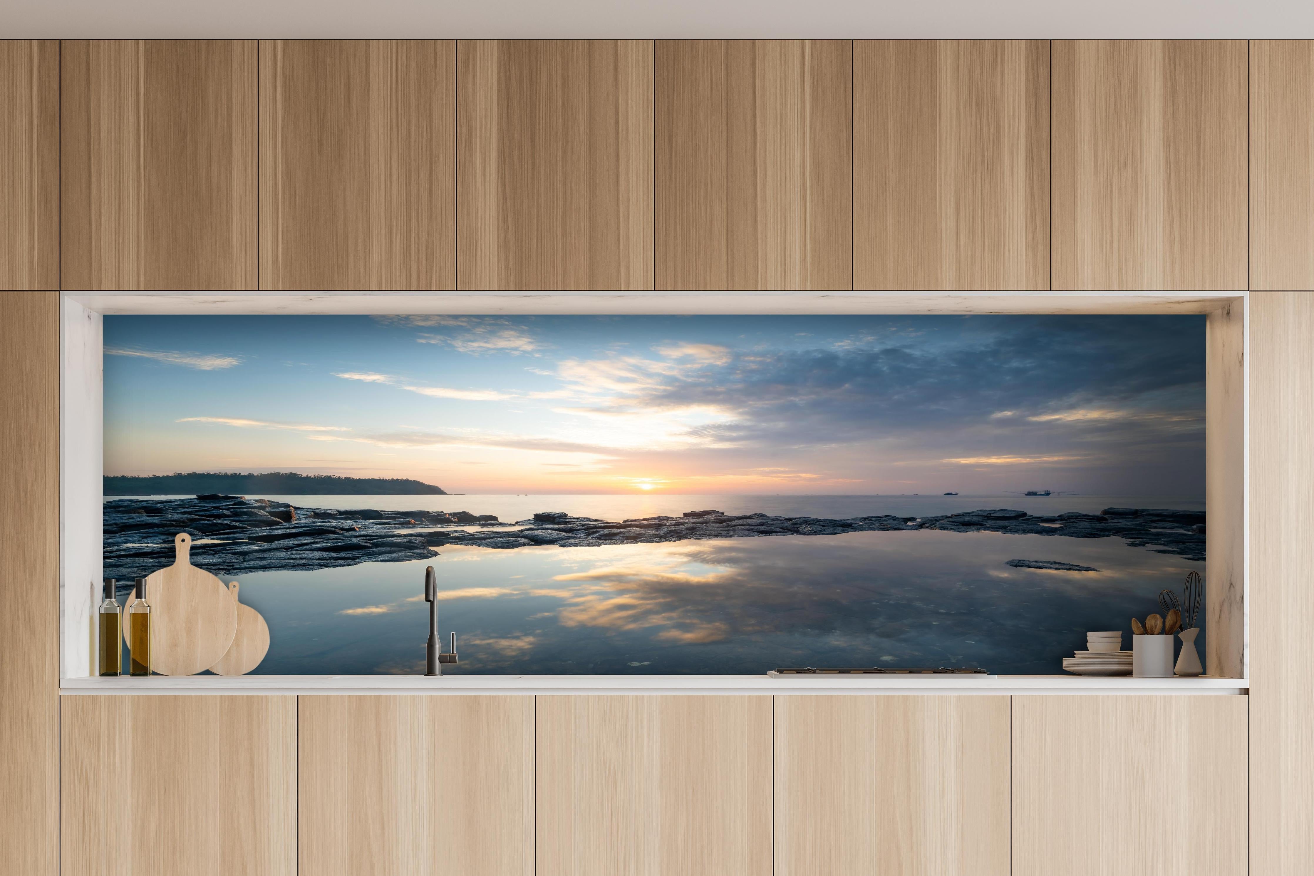 Küche - Pittoresker Sonnenuntergang über dem ruhigen Meer mit reflektierendem Wasser hinter weißen Hochglanz-Küchenregalen und schwarzem Wasserhahn