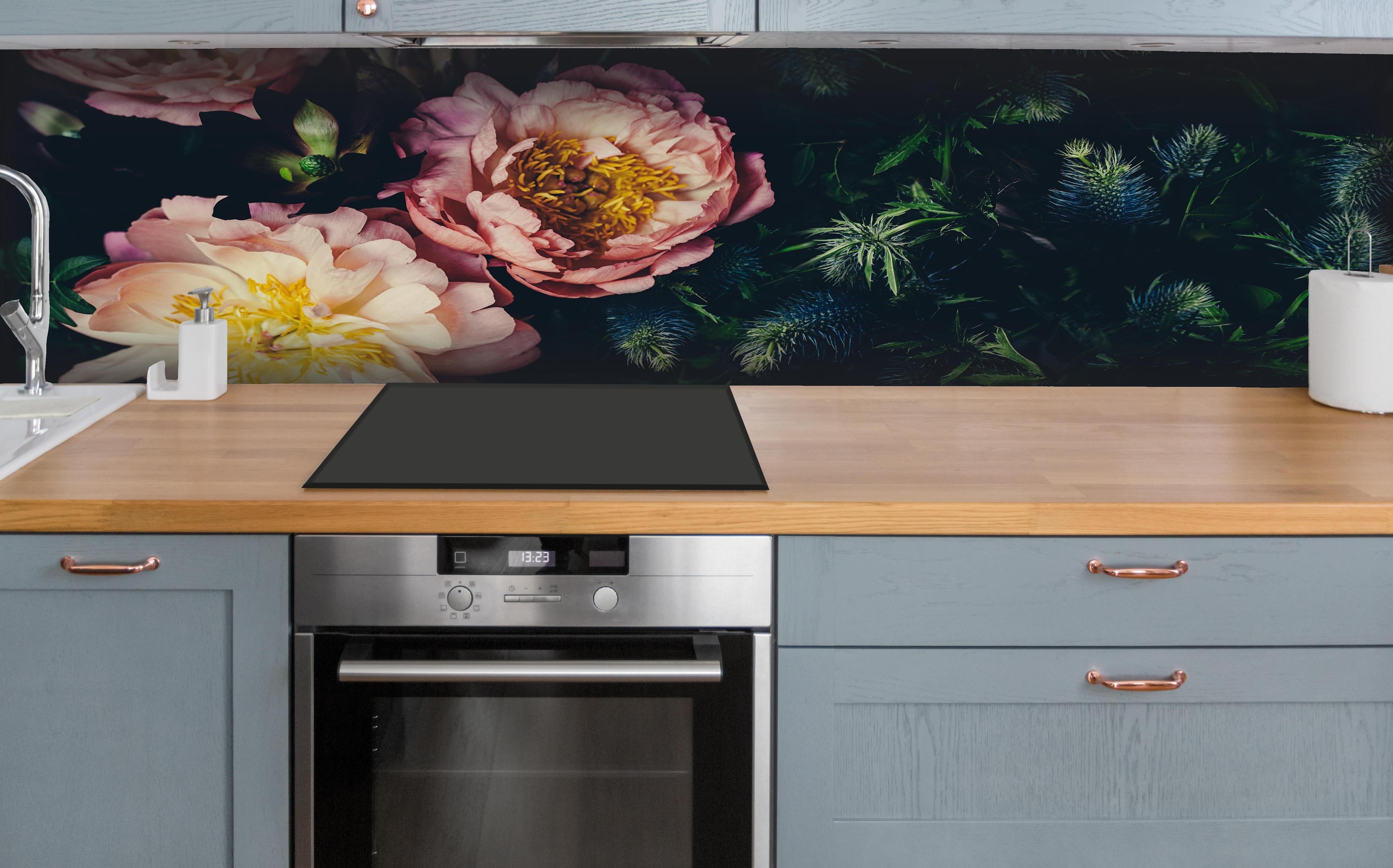 Küche - Rosa Blüten auf einer Wiese hinter weißen Hochglanz-Küchenregalen und schwarzem Wasserhahn