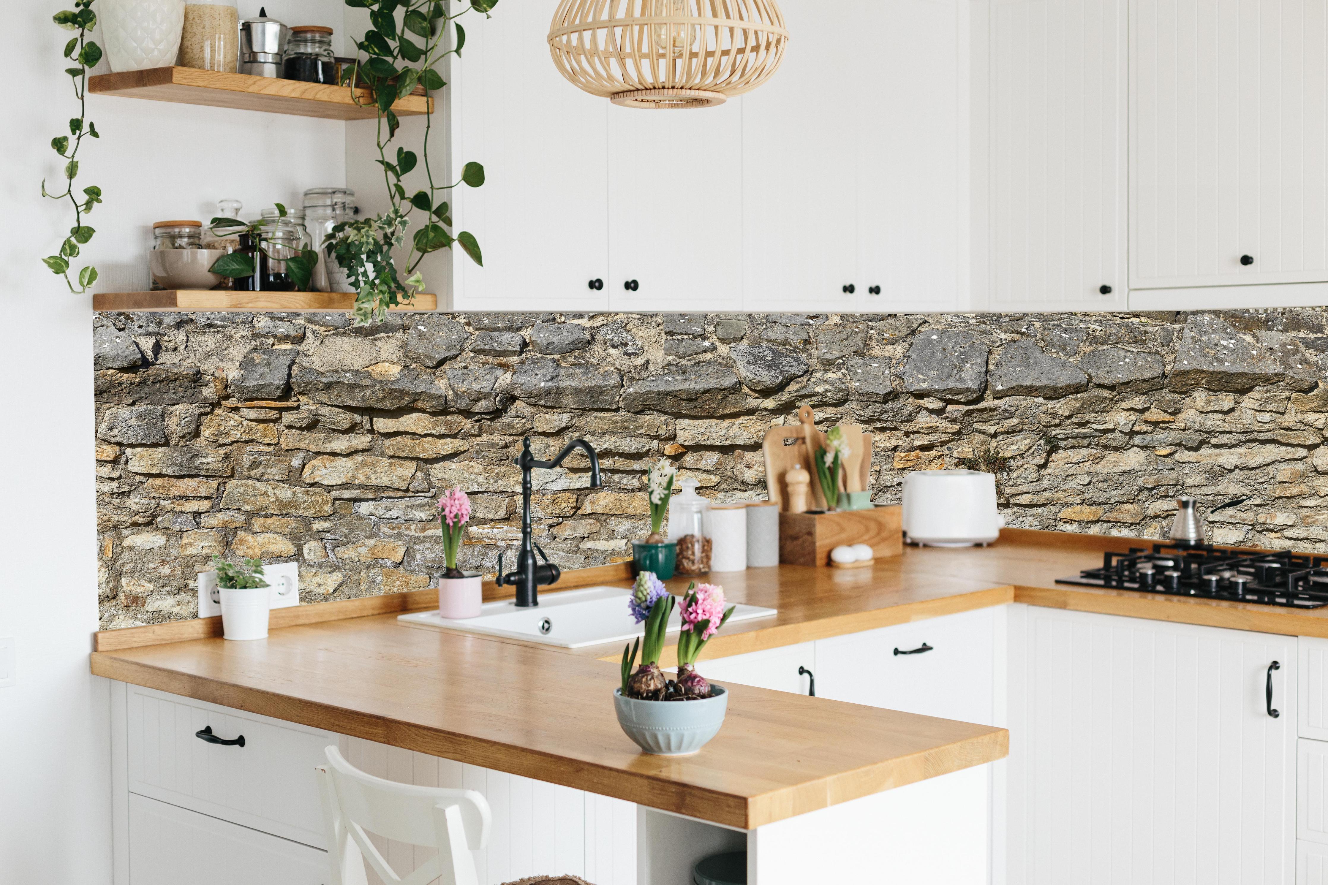 Küche - Rustikale Burgmauer hinter weißen Hochglanz-Küchenregalen und schwarzem Wasserhahn