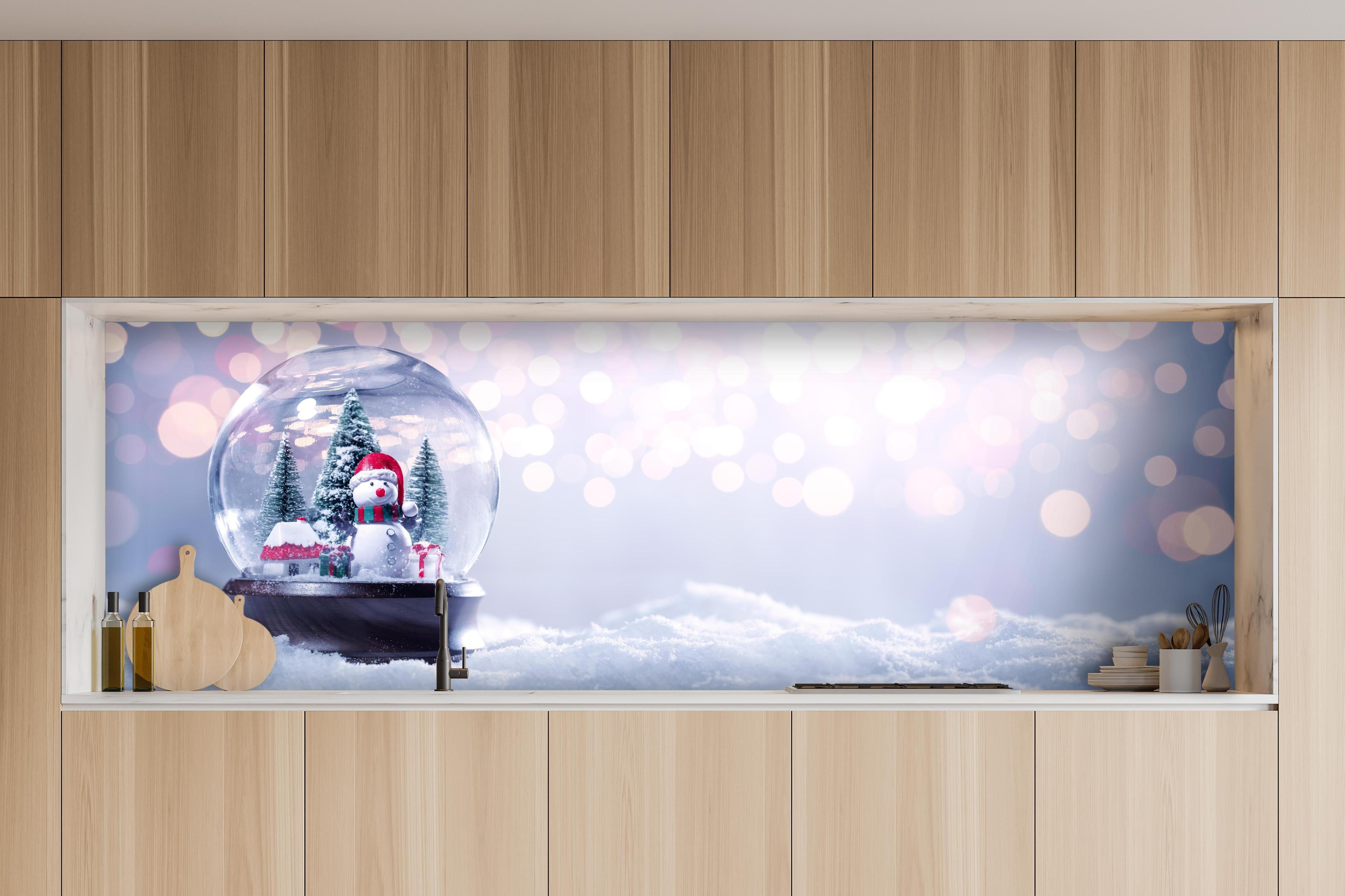 Küche - Schneekugel auf festlichem Hintergrund hinter weißen Hochglanz-Küchenregalen und schwarzem Wasserhahn
