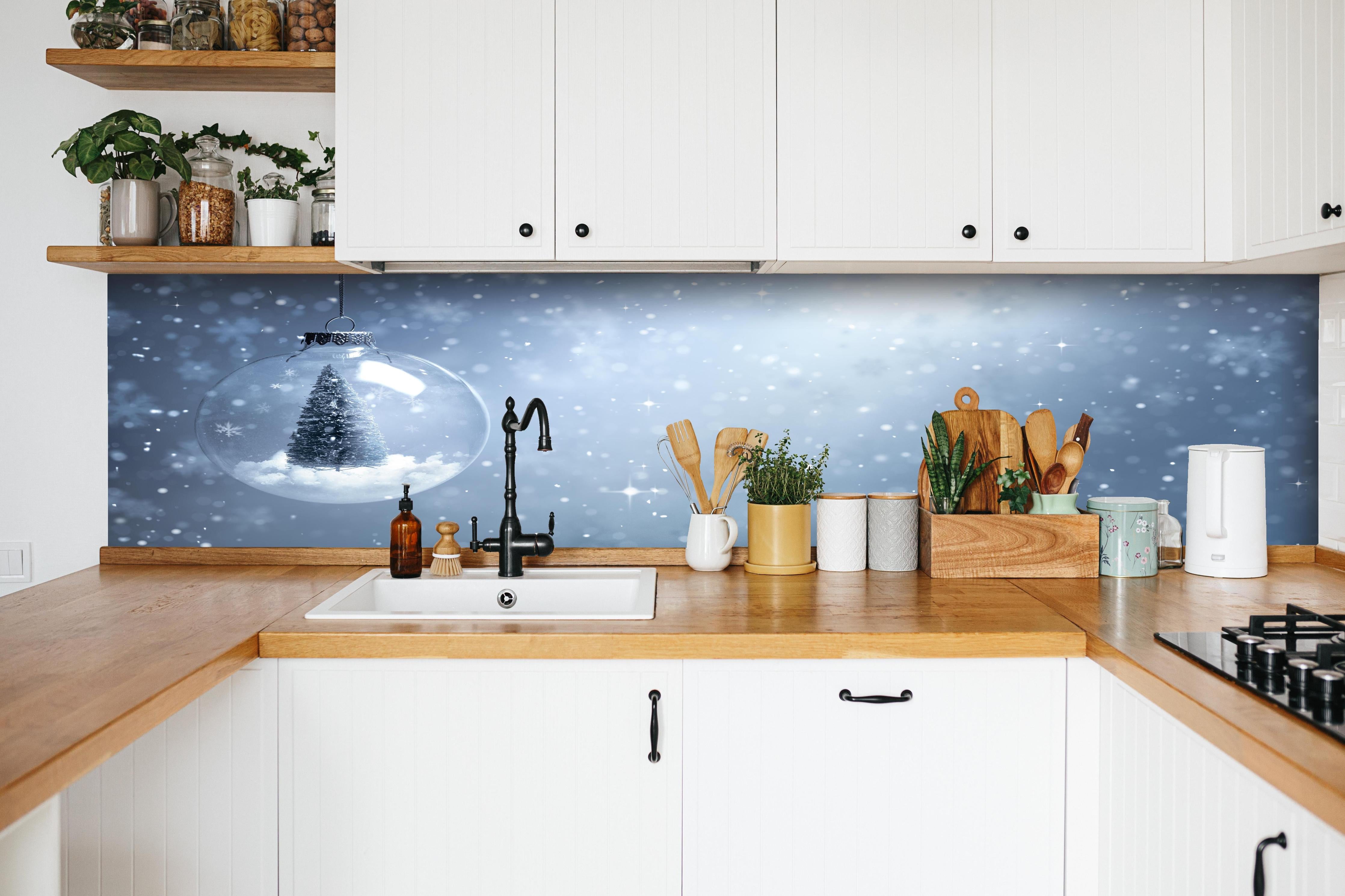 Küche - Schneekugel mit Weihnachtsbaum hinter weißen Hochglanz-Küchenregalen und schwarzem Wasserhahn