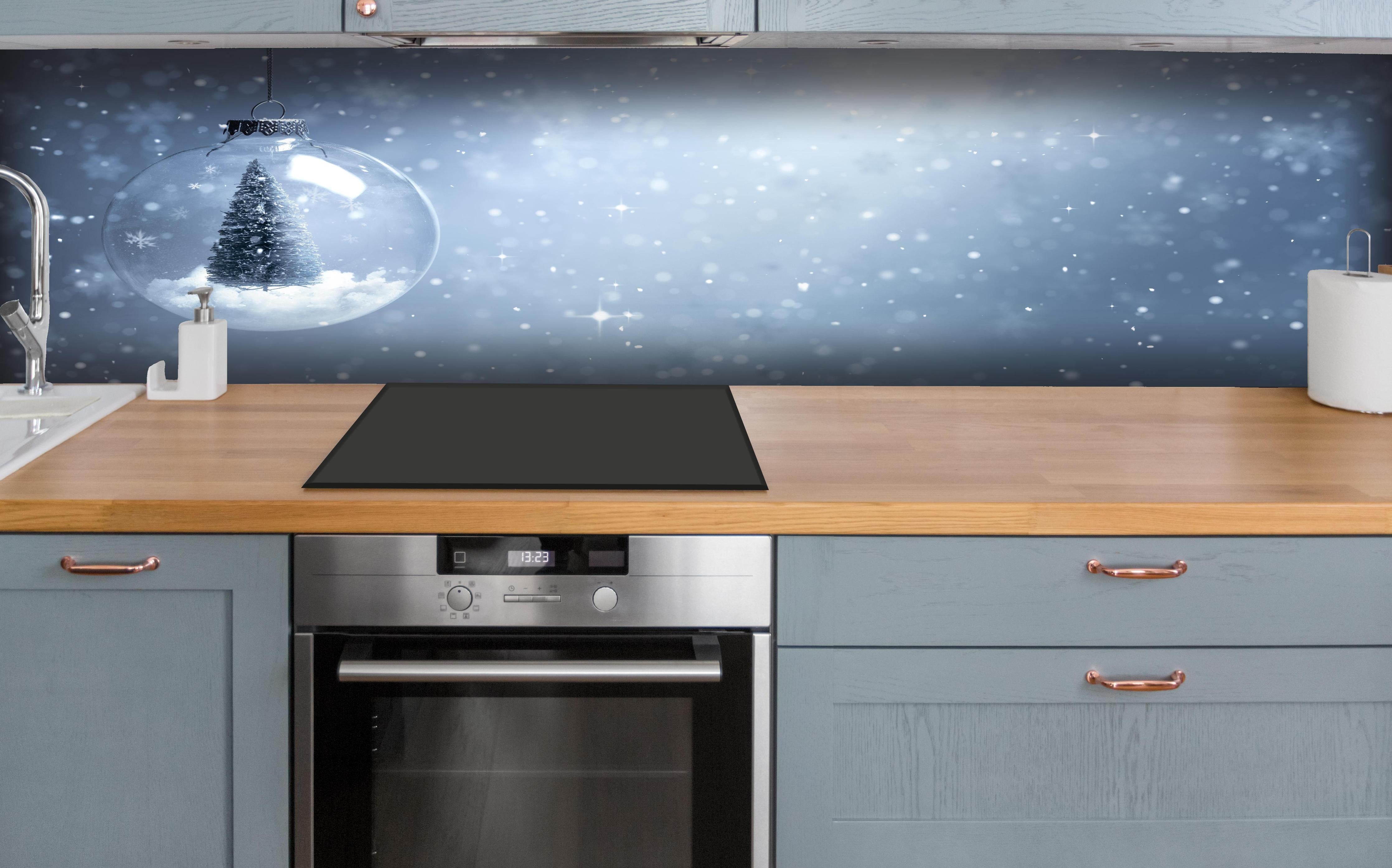 Küche - Schneekugel mit Weihnachtsbaum hinter weißen Hochglanz-Küchenregalen und schwarzem Wasserhahn