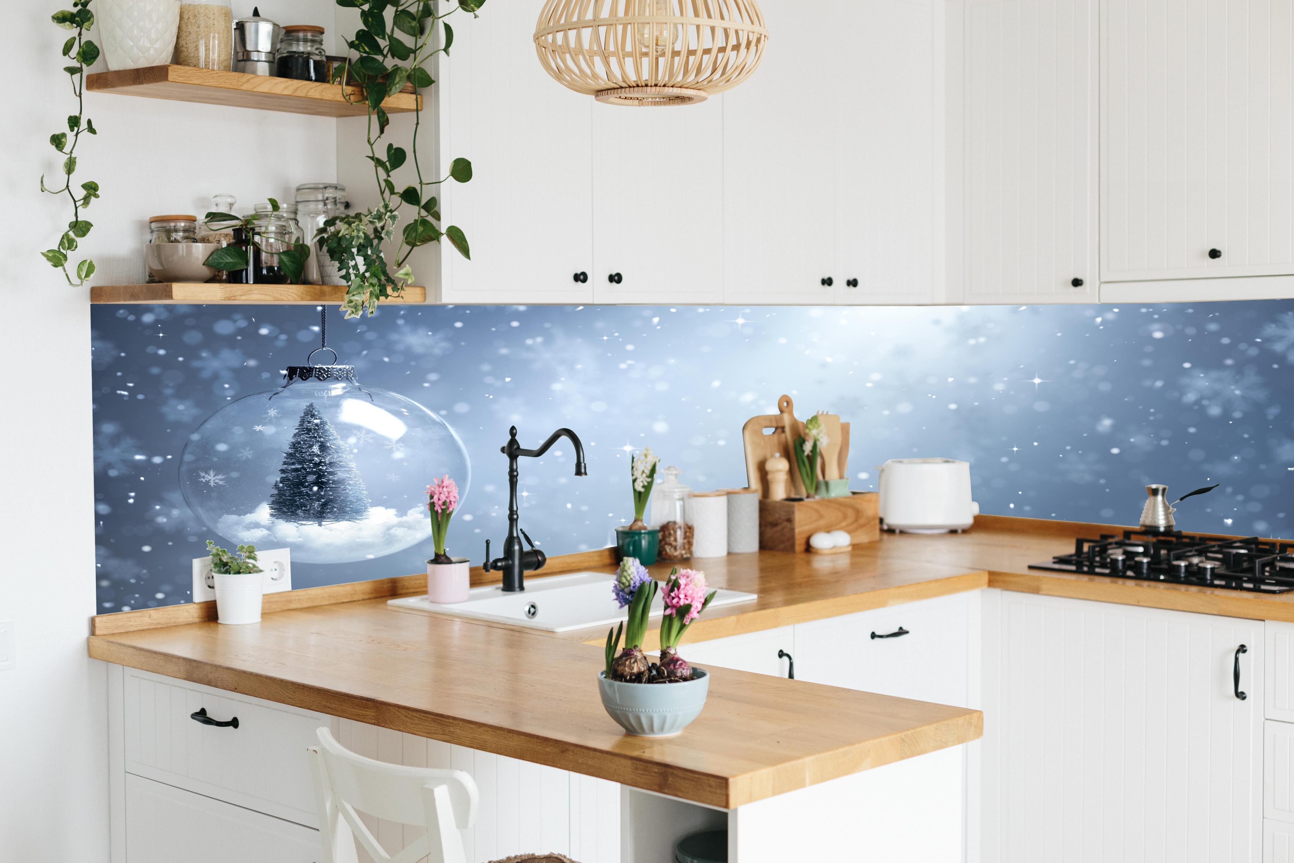 Küche - Schneekugel mit Weihnachtsbaum hinter weißen Hochglanz-Küchenregalen und schwarzem Wasserhahn