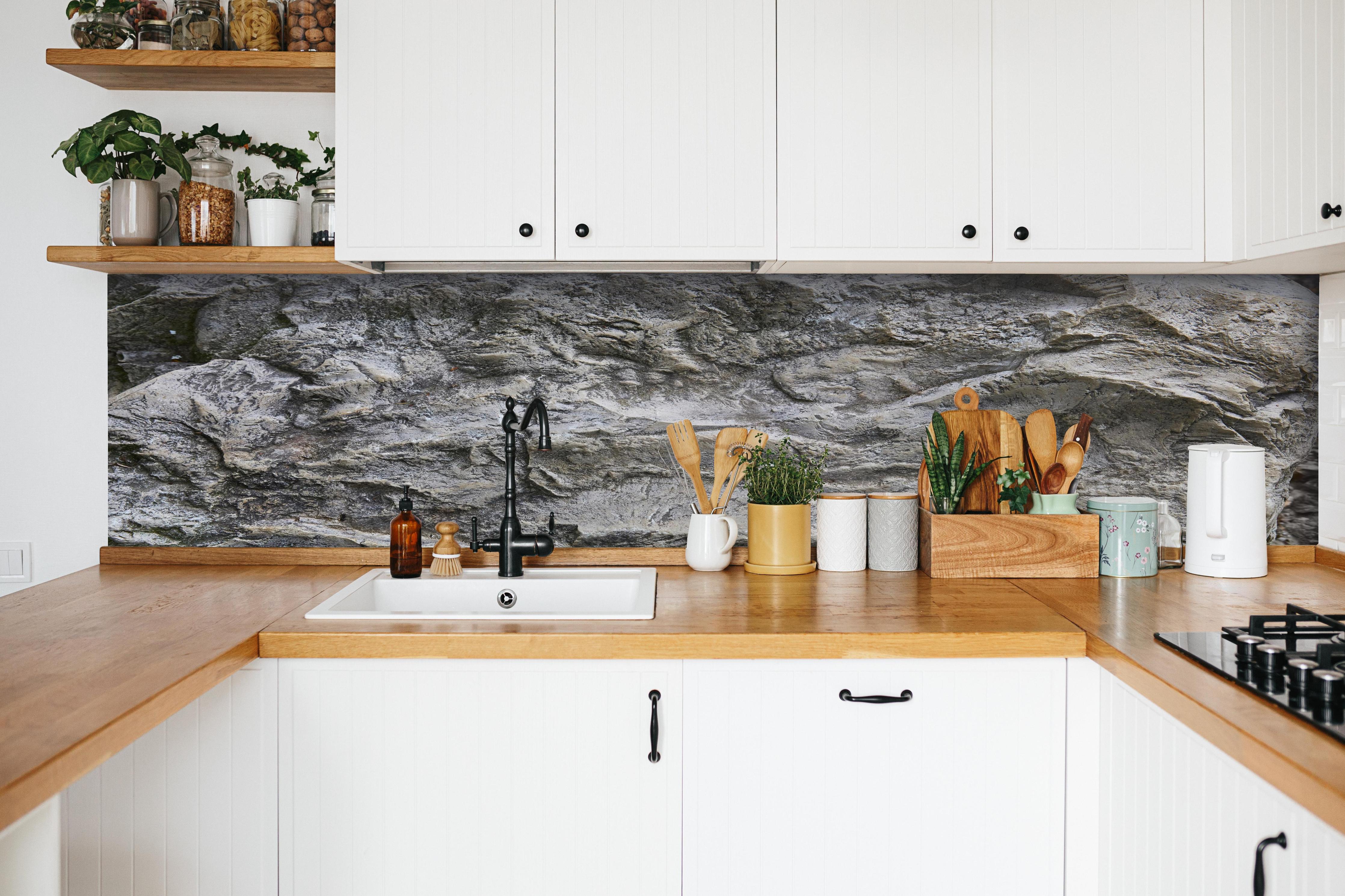 Küche - Schöne Felsstruktur - Granit hinter weißen Hochglanz-Küchenregalen und schwarzem Wasserhahn