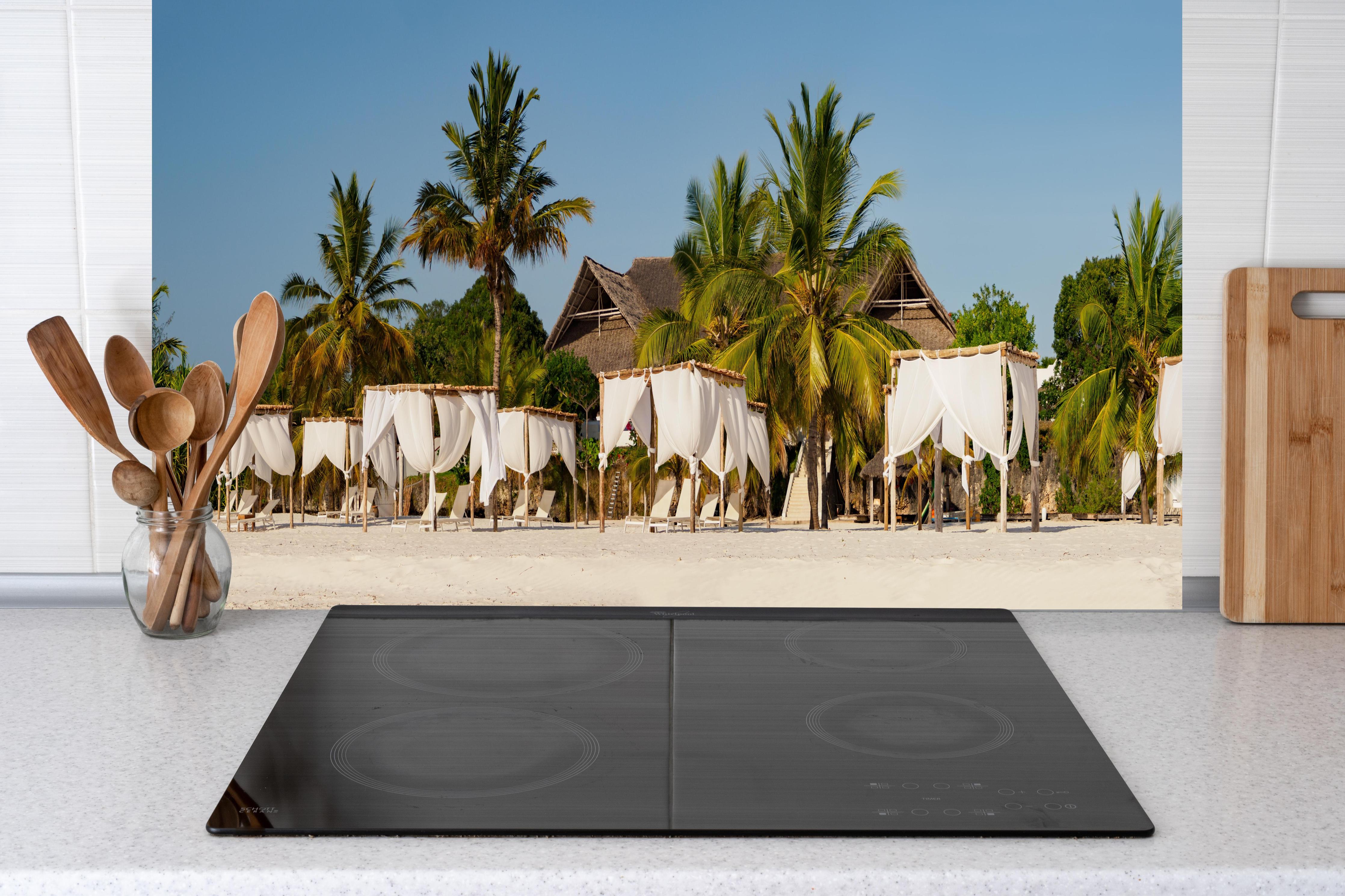 Küche - Schöner Strand mit Liegen  hinter weißen Hochglanz-Küchenregalen und schwarzem Wasserhahn