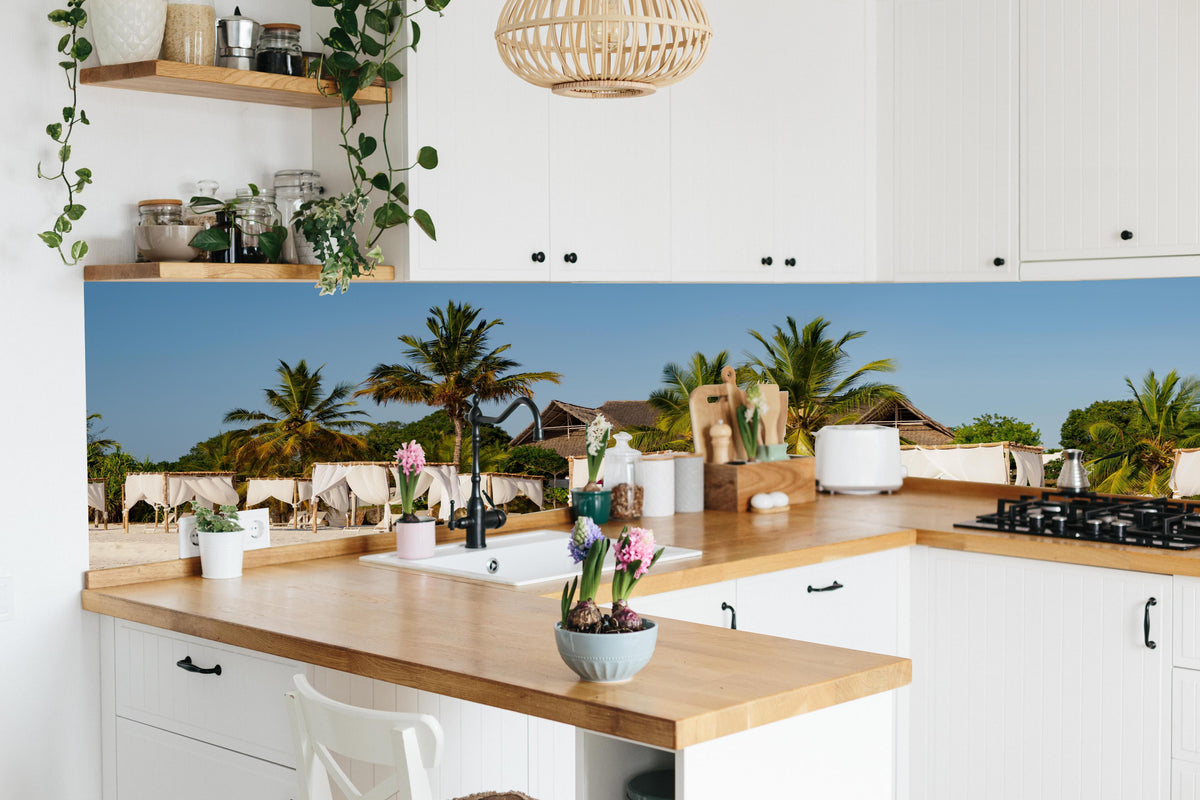 Küche - Schöner Strand mit Liegen  hinter weißen Hochglanz-Küchenregalen und schwarzem Wasserhahn