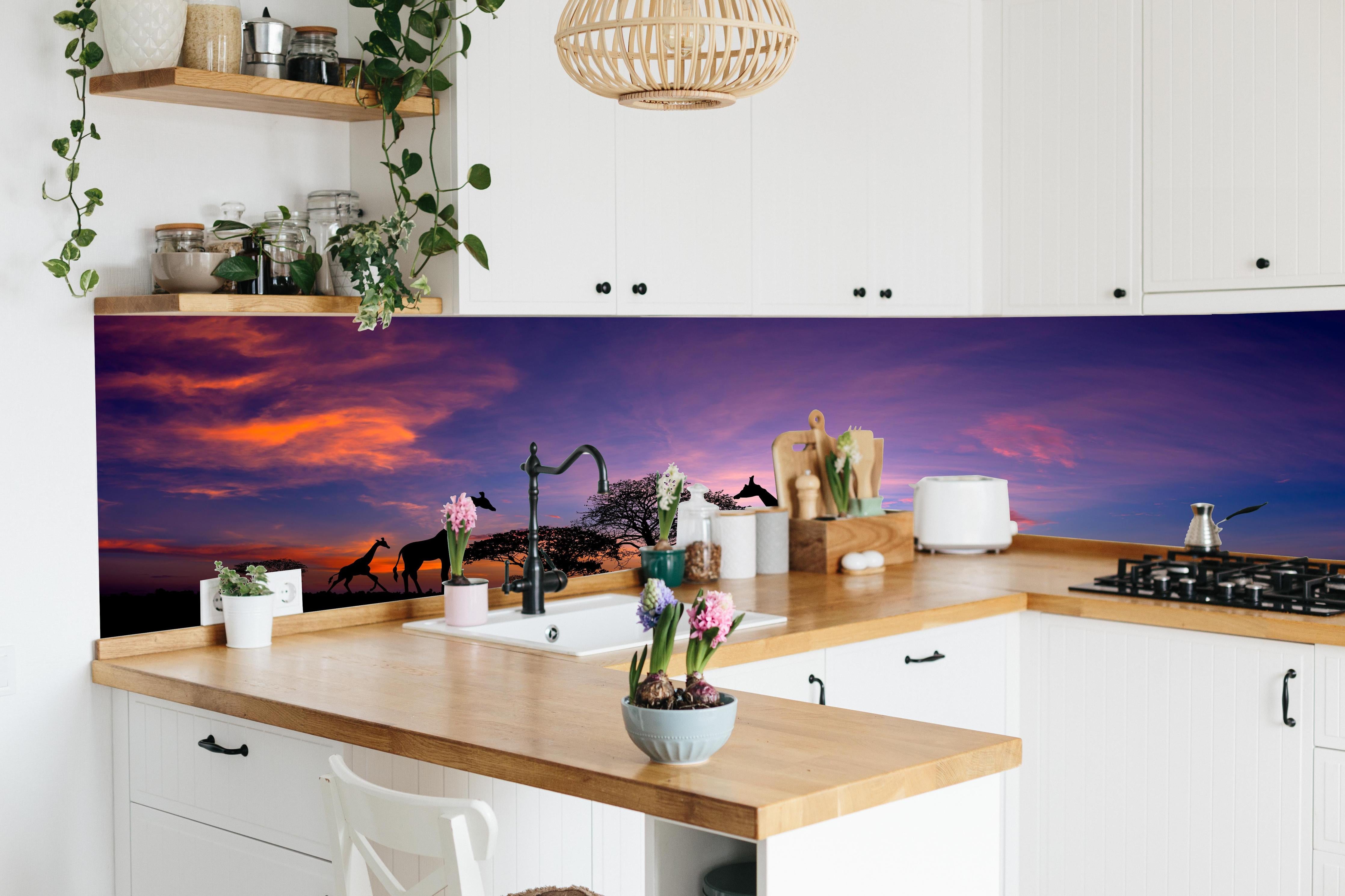 Küche - Silhouette - Giraffenfamilie bei Sonnenuntergang hinter weißen Hochglanz-Küchenregalen und schwarzem Wasserhahn