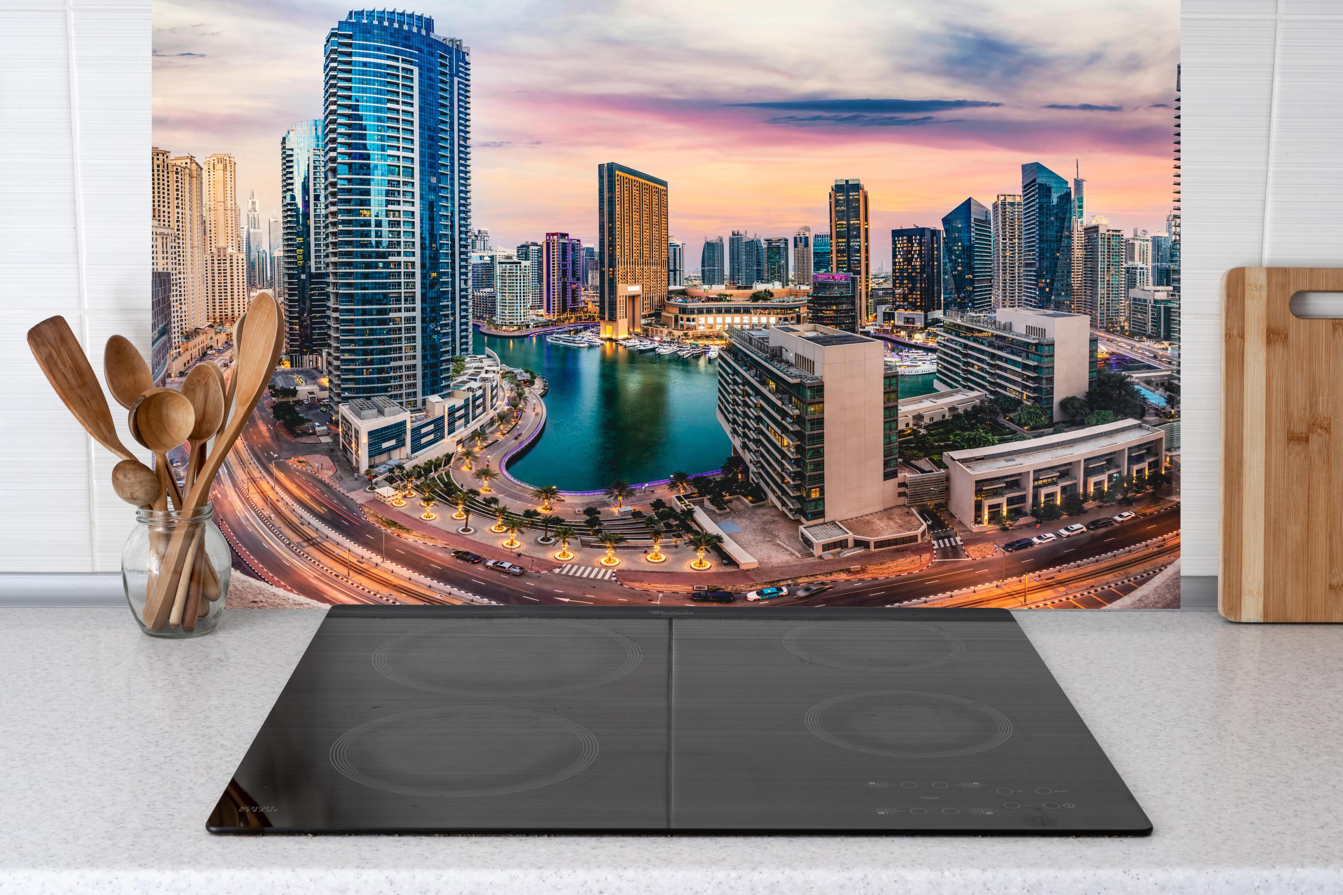 Küche - Skyline des Jachthafens von Dubai bei Sonnenuntergang hinter weißen Hochglanz-Küchenregalen und schwarzem Wasserhahn