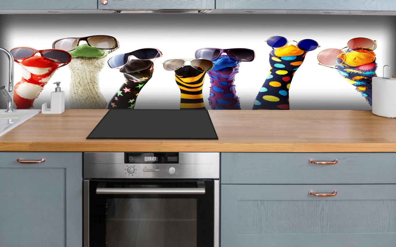 Küche - Sockenpuppen mit Brille hinter weißen Hochglanz-Küchenregalen und schwarzem Wasserhahn