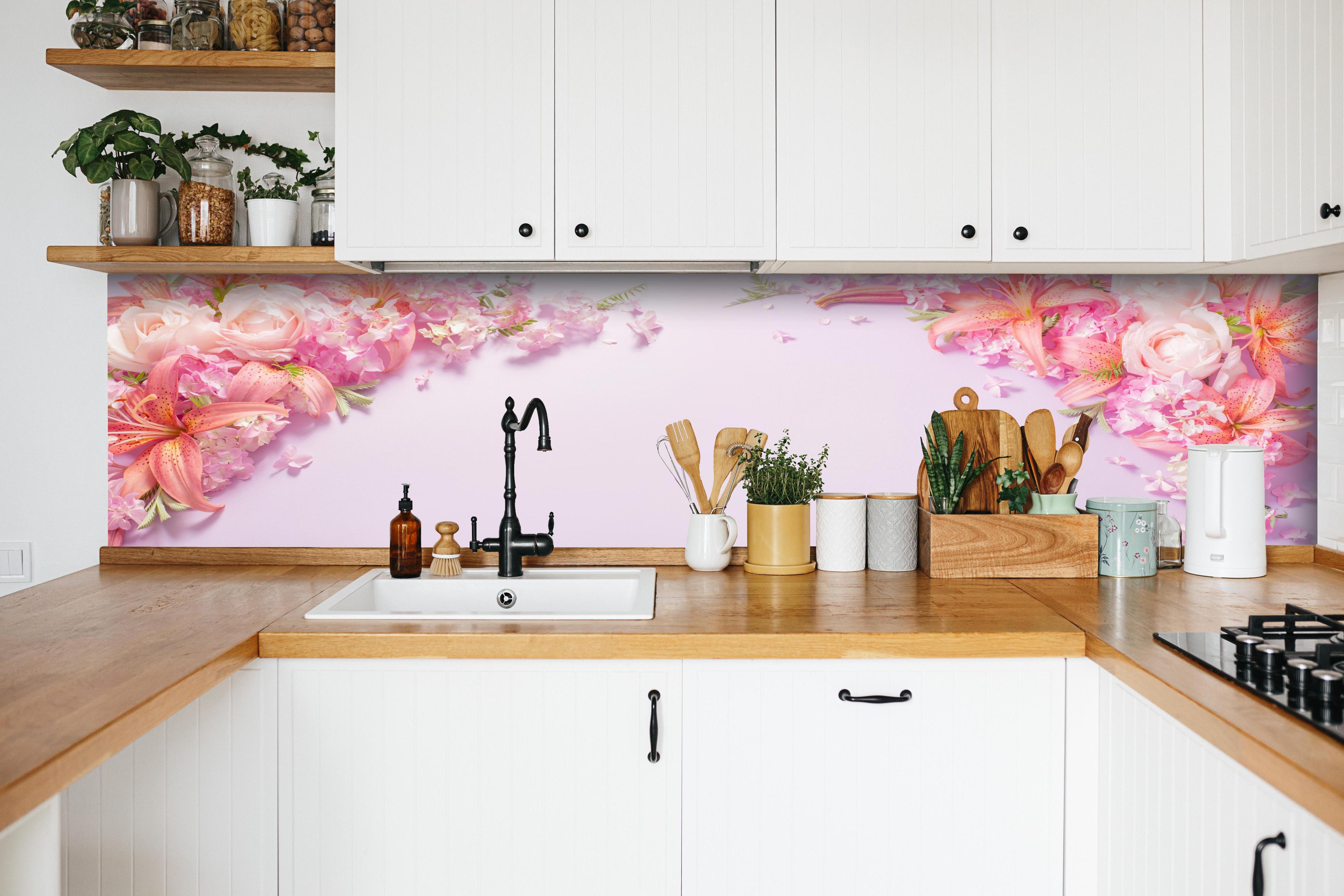 Küche - Sommerliche Blumenarrangements auf Papier hinter weißen Hochglanz-Küchenregalen und schwarzem Wasserhahn