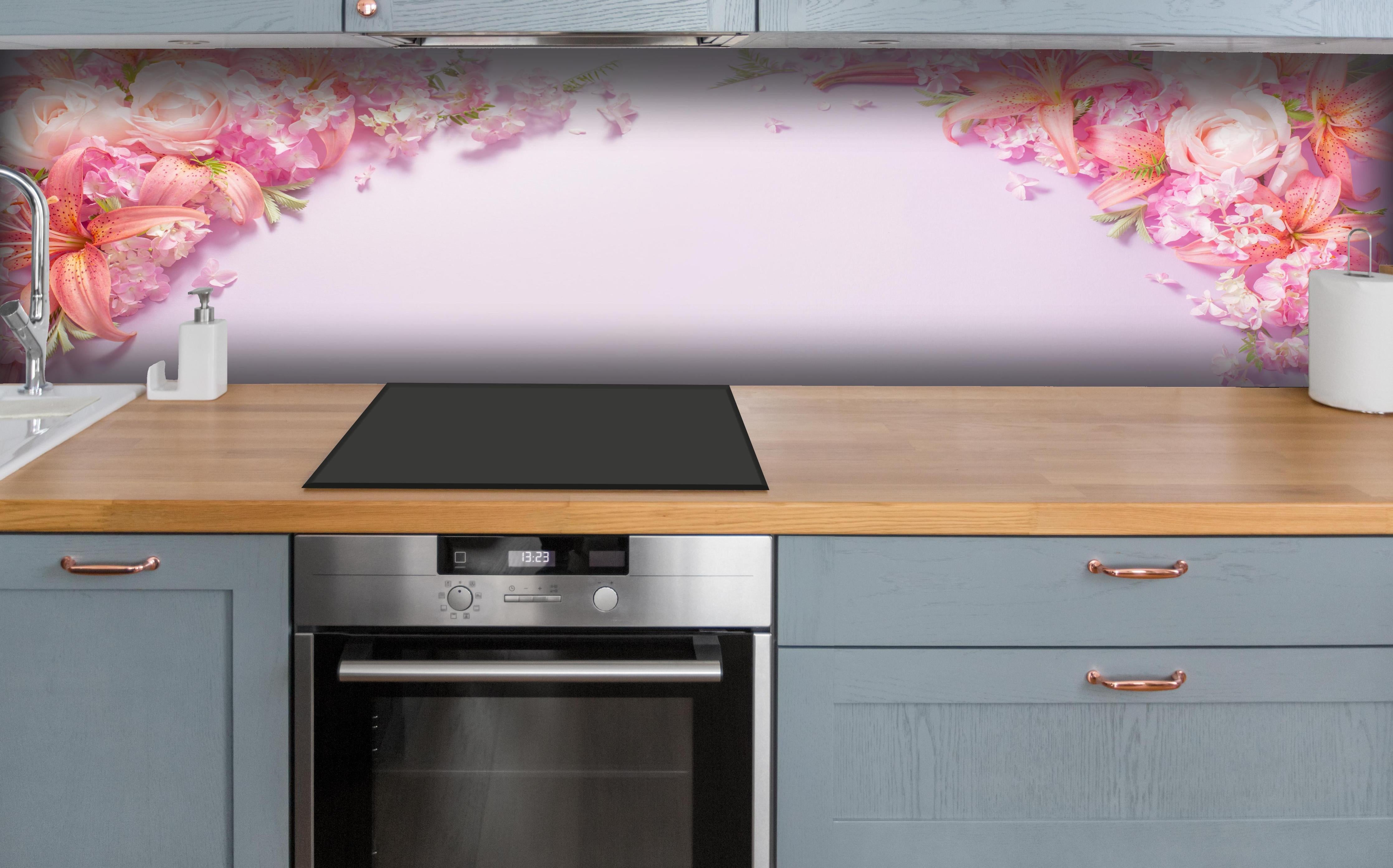 Küche - Sommerliche Blumenarrangements auf Papier hinter weißen Hochglanz-Küchenregalen und schwarzem Wasserhahn