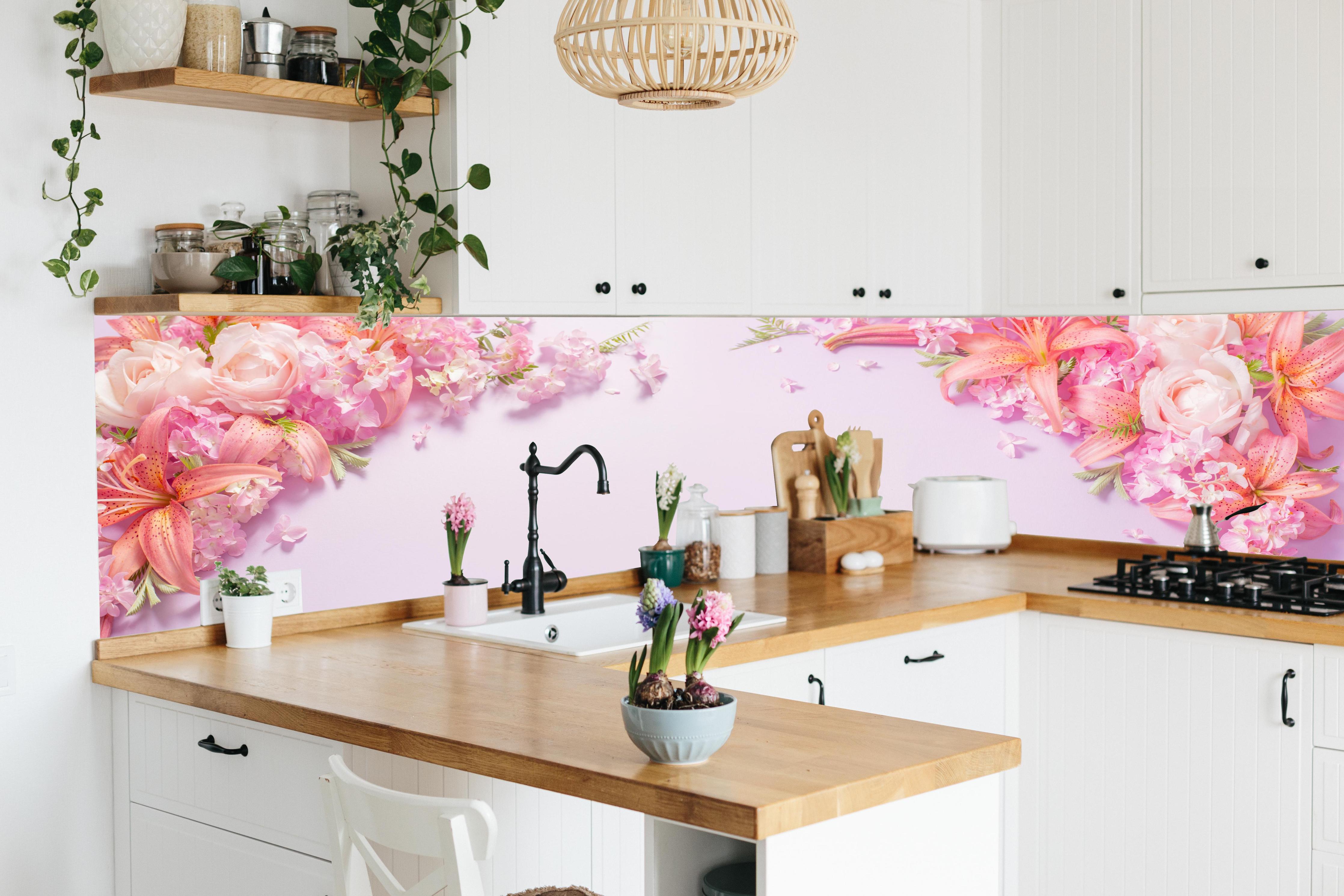 Küche - Sommerliche Blumenarrangements auf Papier hinter weißen Hochglanz-Küchenregalen und schwarzem Wasserhahn