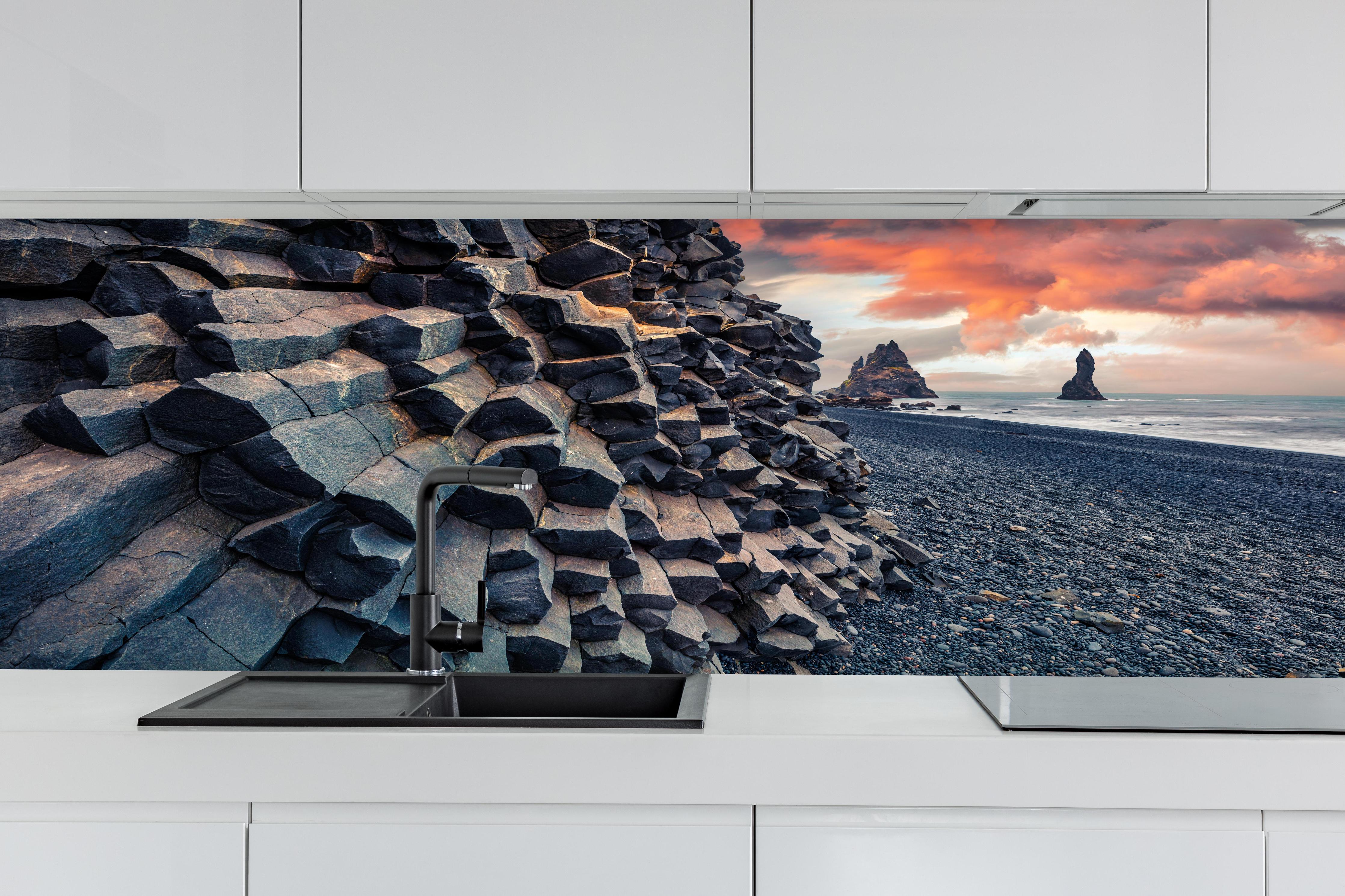 Küche - Sonnenuntergang - Reynisdrangar, Atlantischer Ozean hinter weißen Hochglanz-Küchenregalen und schwarzem Wasserhahn