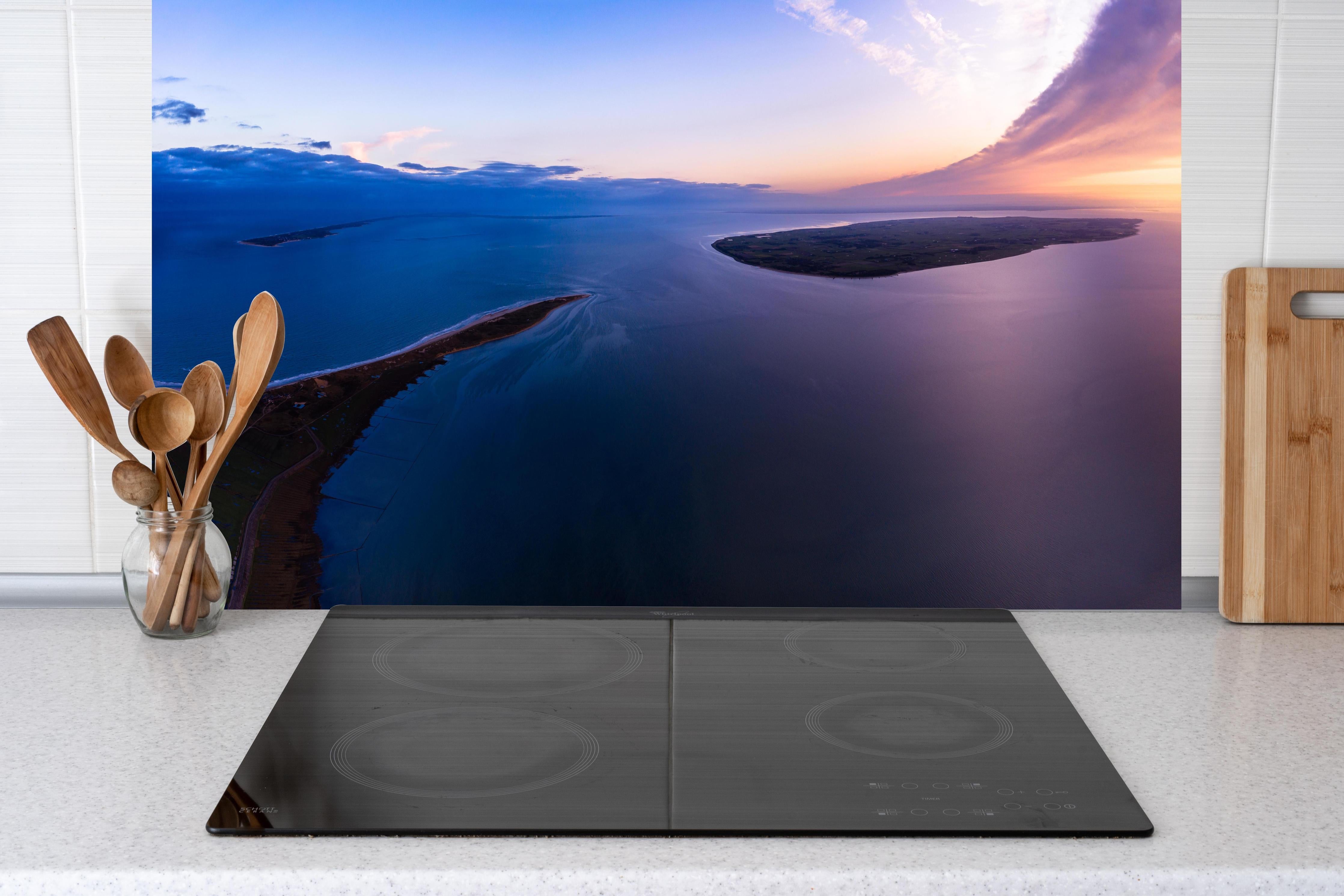 Küche - Spektakulärer Sonnenuntergang über ruhigem Gewässer und unberührten Inseln hinter weißen Hochglanz-Küchenregalen und schwarzem Wasserhahn