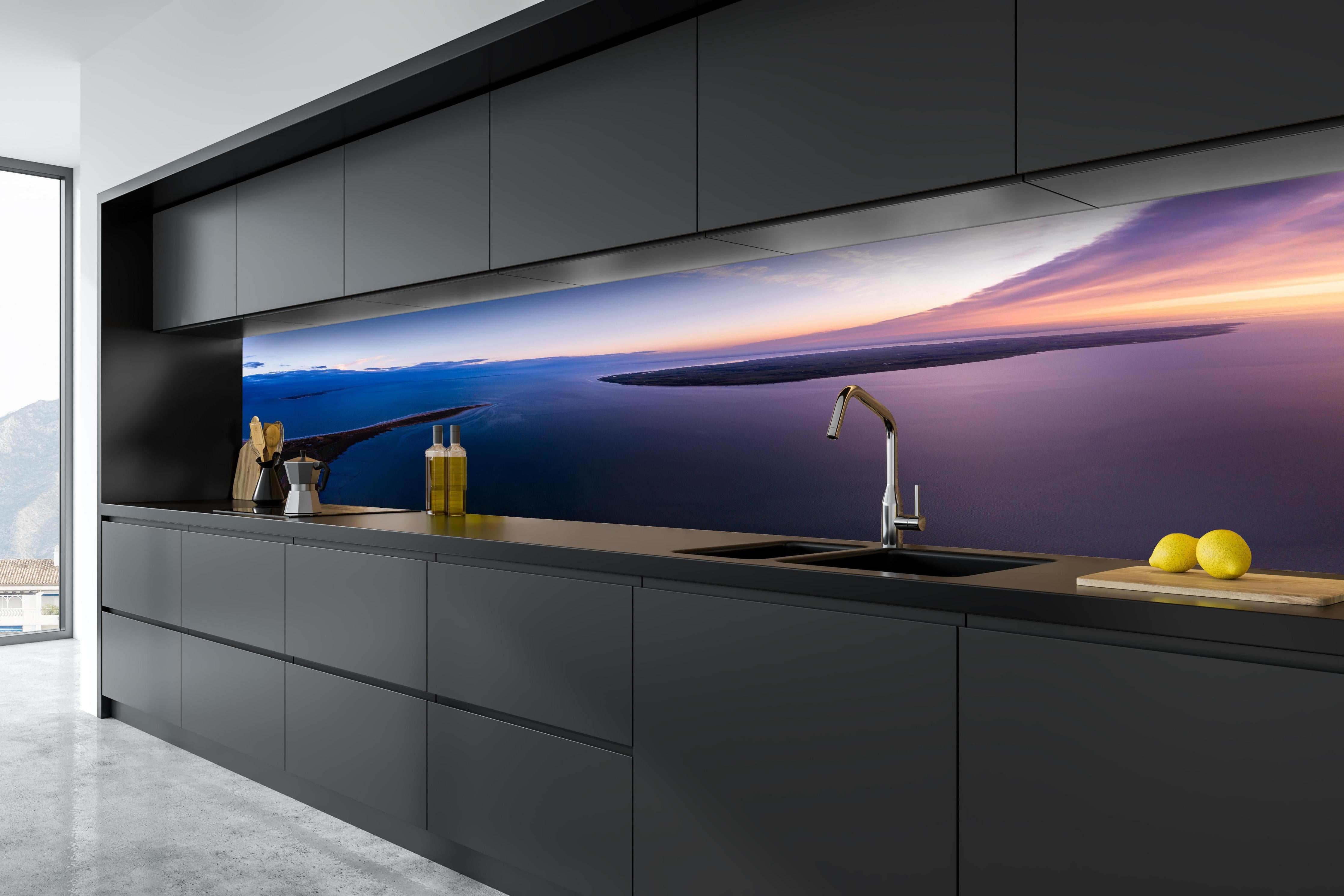 Küche - Spektakulärer Sonnenuntergang über ruhigem Gewässer und unberührten Inseln hinter weißen Hochglanz-Küchenregalen und schwarzem Wasserhahn