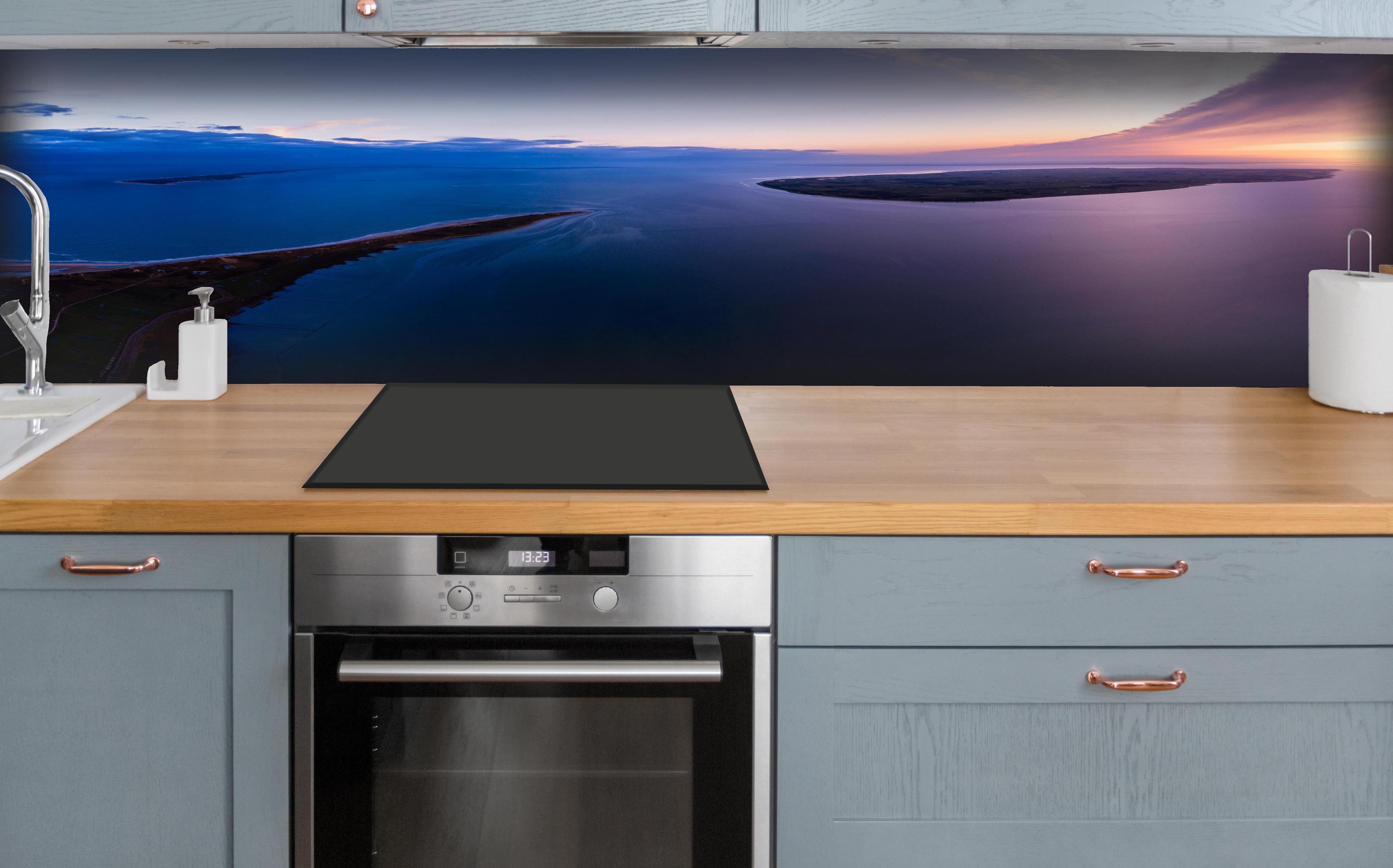 Küche - Spektakulärer Sonnenuntergang über ruhigem Gewässer und unberührten Inseln hinter weißen Hochglanz-Küchenregalen und schwarzem Wasserhahn