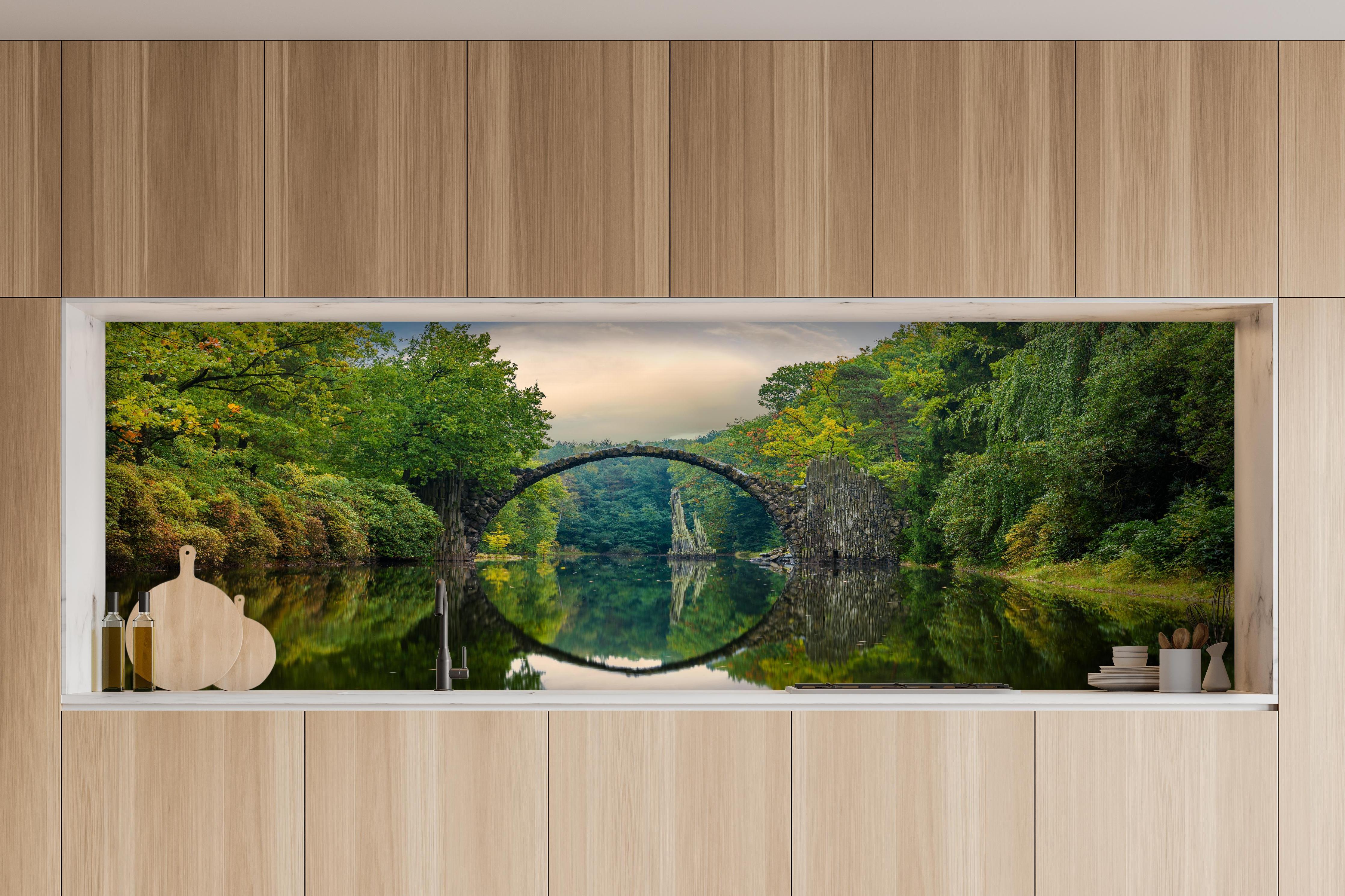 Küche - Steinbrücke über Fluss im Wald hinter weißen Hochglanz-Küchenregalen und schwarzem Wasserhahn