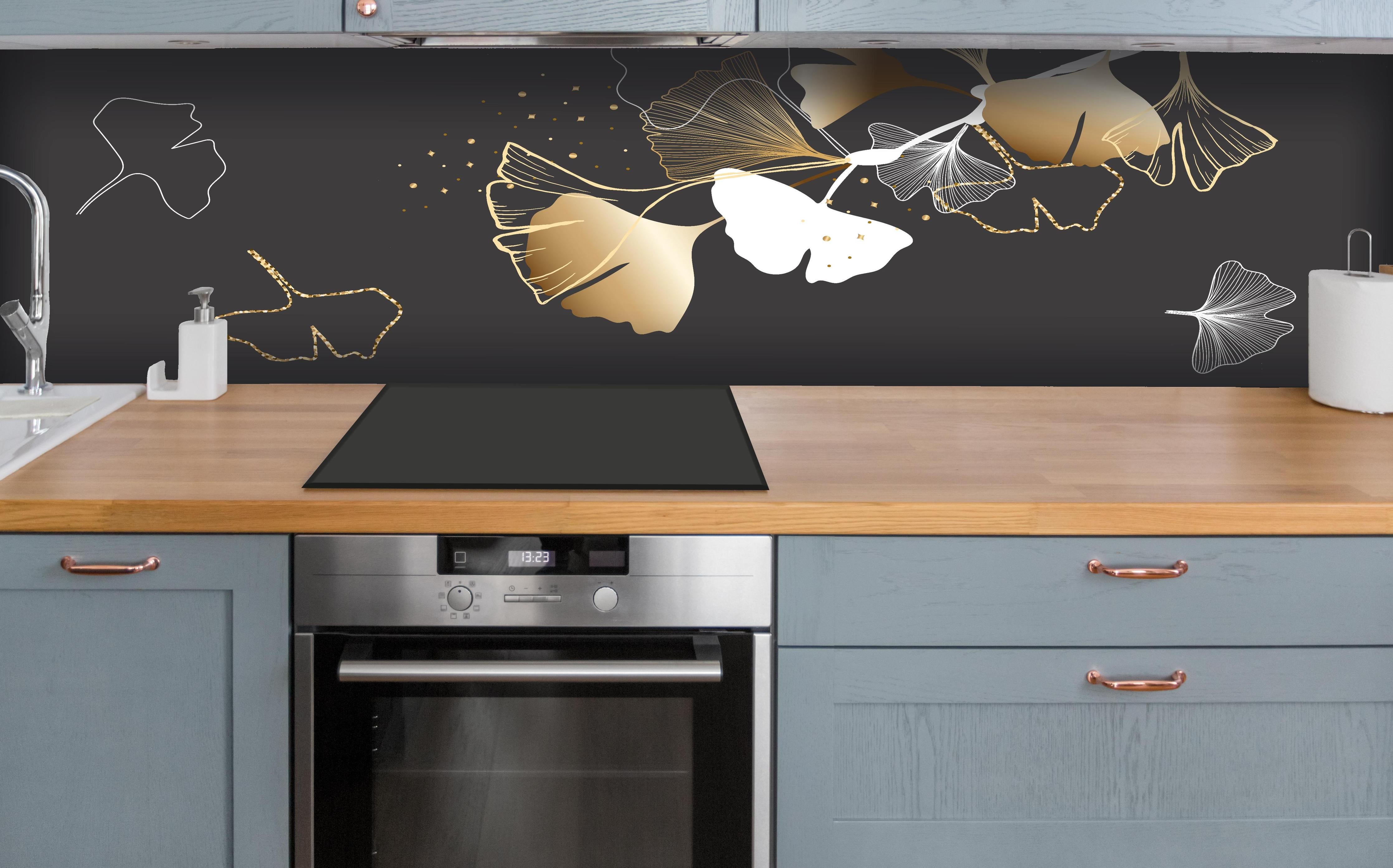 Küche - Stilisiertes Ginkgo-Design in Gold und Schwarz hinter weißen Hochglanz-Küchenregalen und schwarzem Wasserhahn