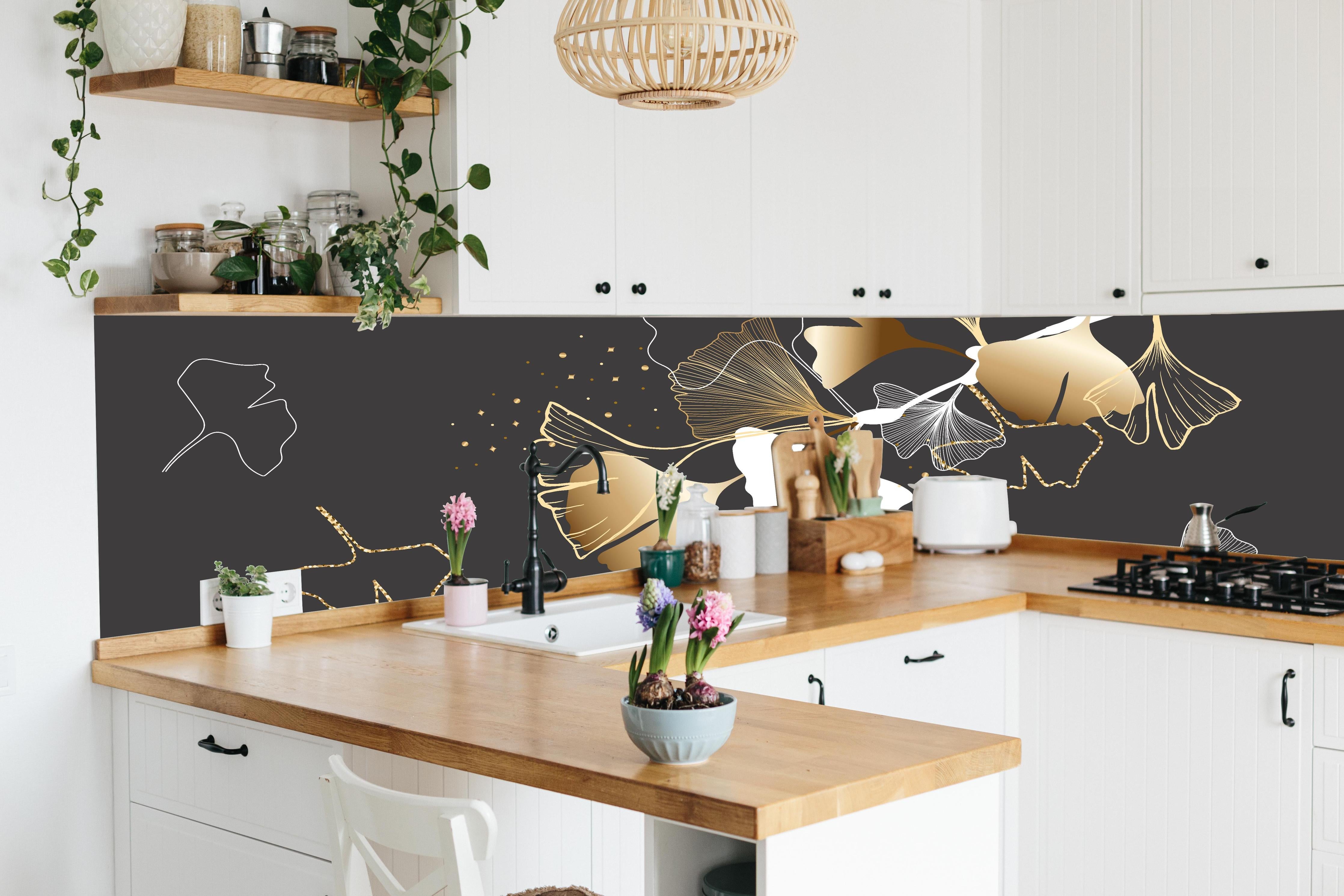 Küche - Stilisiertes Ginkgo-Design in Gold und Schwarz hinter weißen Hochglanz-Küchenregalen und schwarzem Wasserhahn