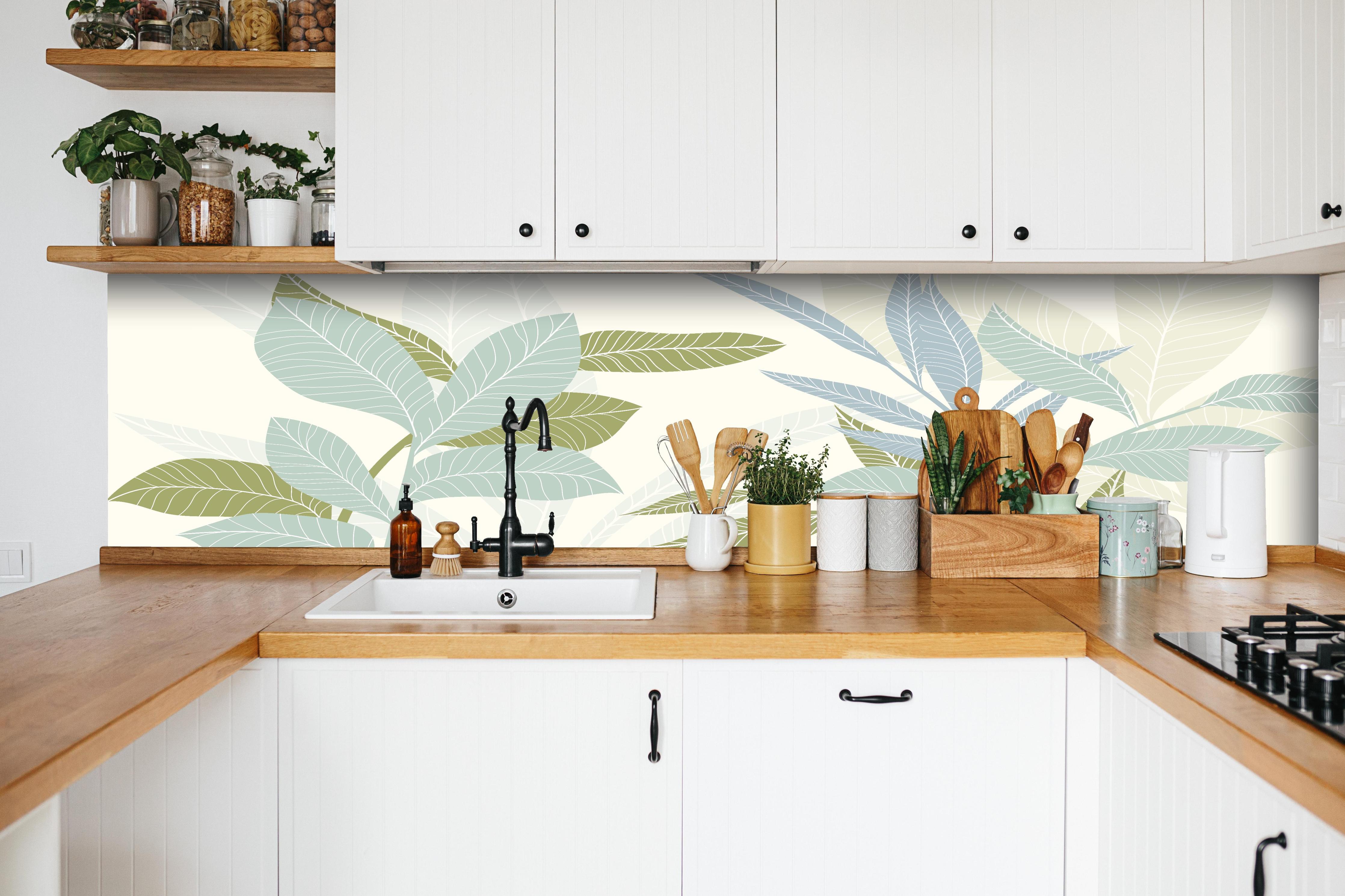 Küche - Stilvolles Blatt-Design in Pastelltönen hinter weißen Hochglanz-Küchenregalen und schwarzem Wasserhahn