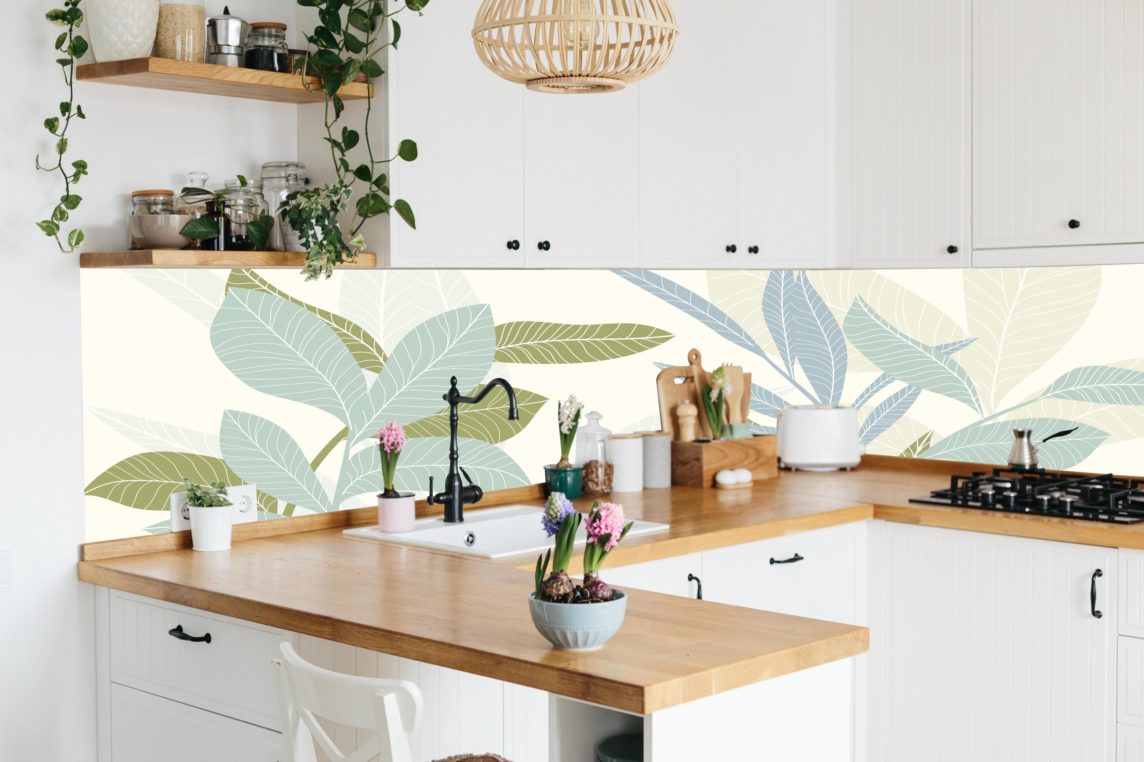 Küche - Stilvolles Blatt-Design in Pastelltönen hinter weißen Hochglanz-Küchenregalen und schwarzem Wasserhahn