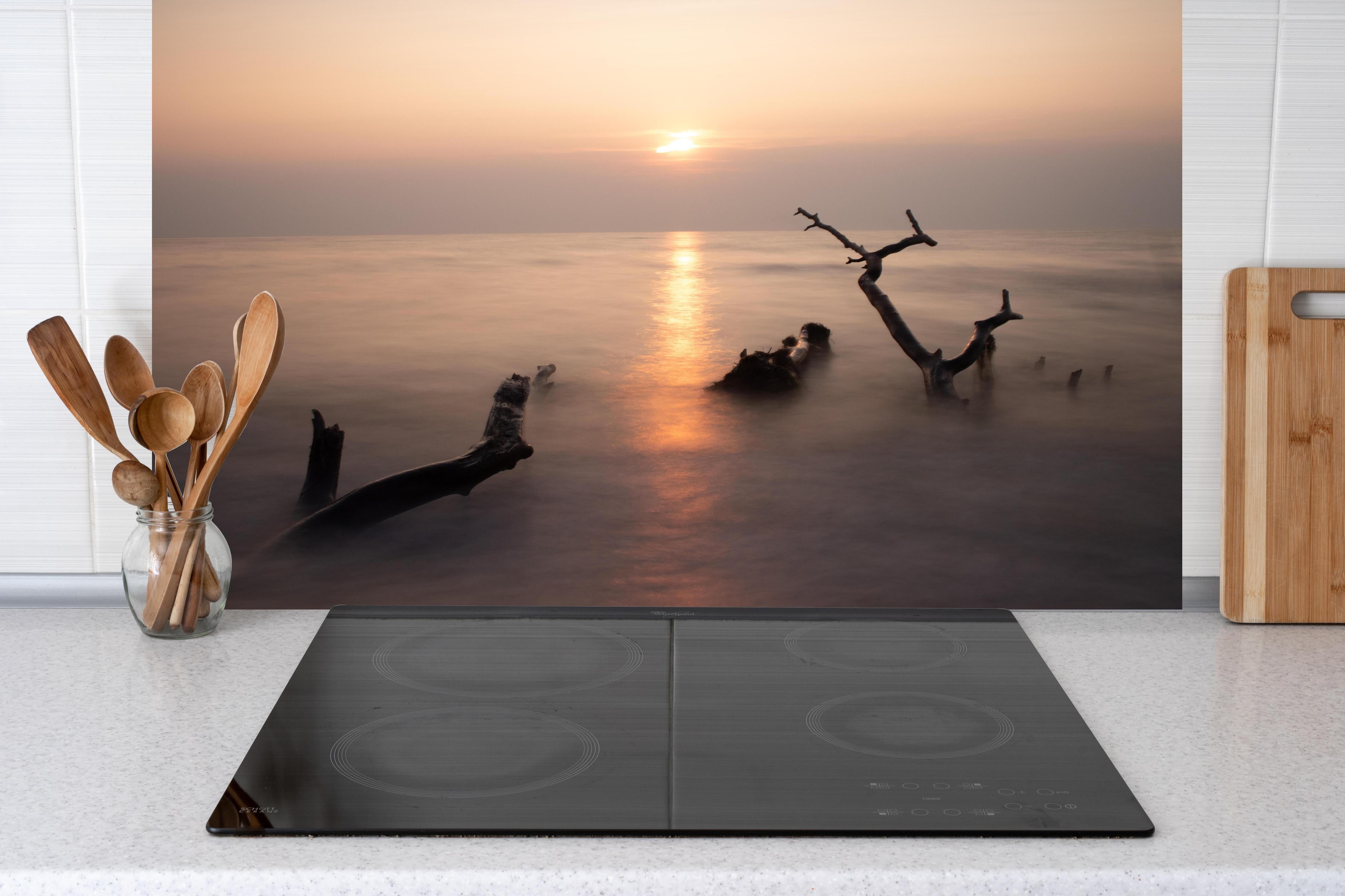 Küche - Stimmungsvoller Sonnenuntergangs-Strand hinter weißen Hochglanz-Küchenregalen und schwarzem Wasserhahn
