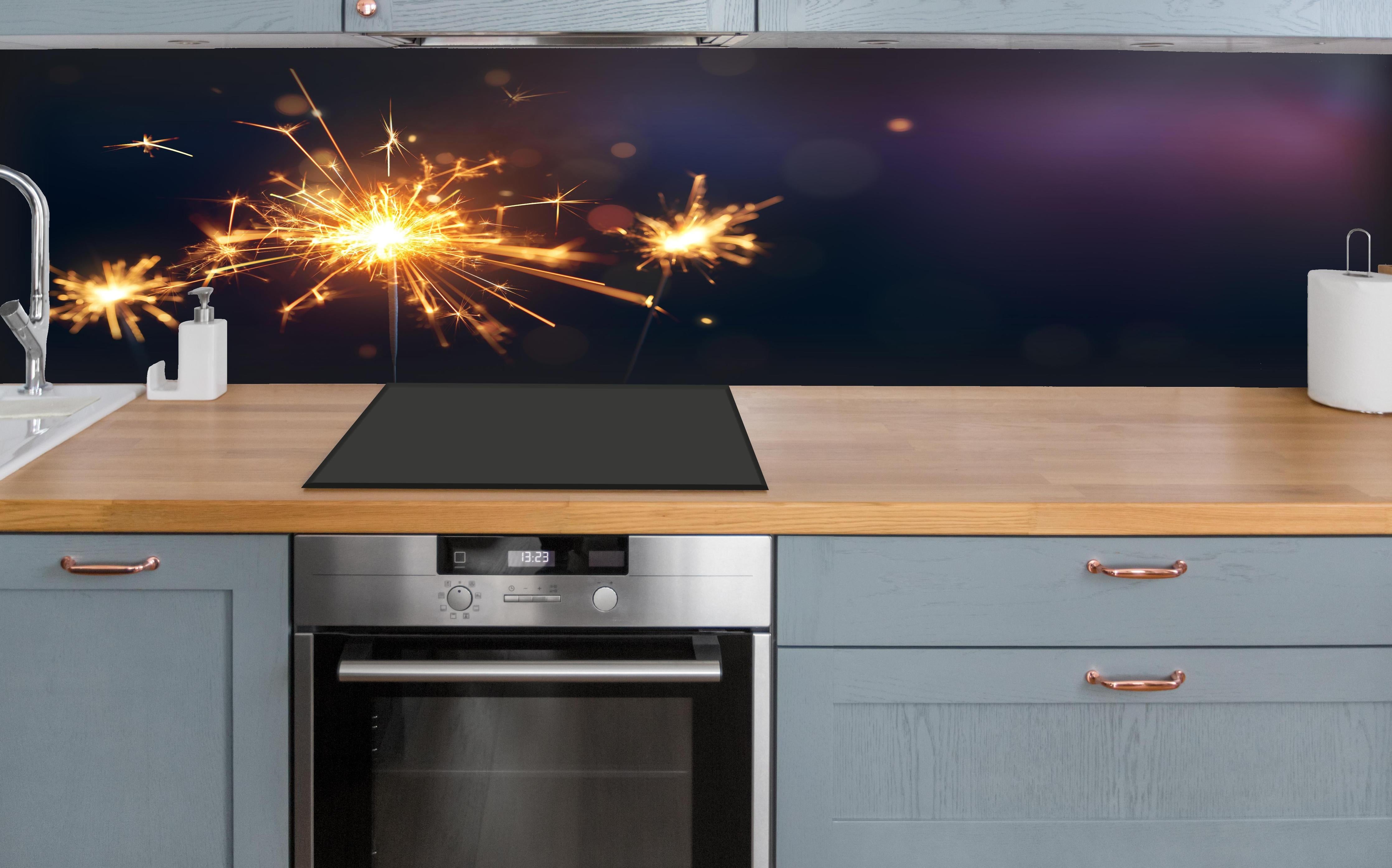 Küche - Strahlendes Wunderkerzen-Goldlichtfeuerwerk hinter weißen Hochglanz-Küchenregalen und schwarzem Wasserhahn