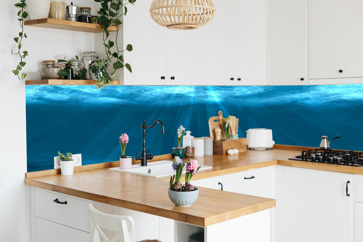 Küche - Taucherparadies in Ozeanblau und Türkis hinter weißen Hochglanz-Küchenregalen und schwarzem Wasserhahn