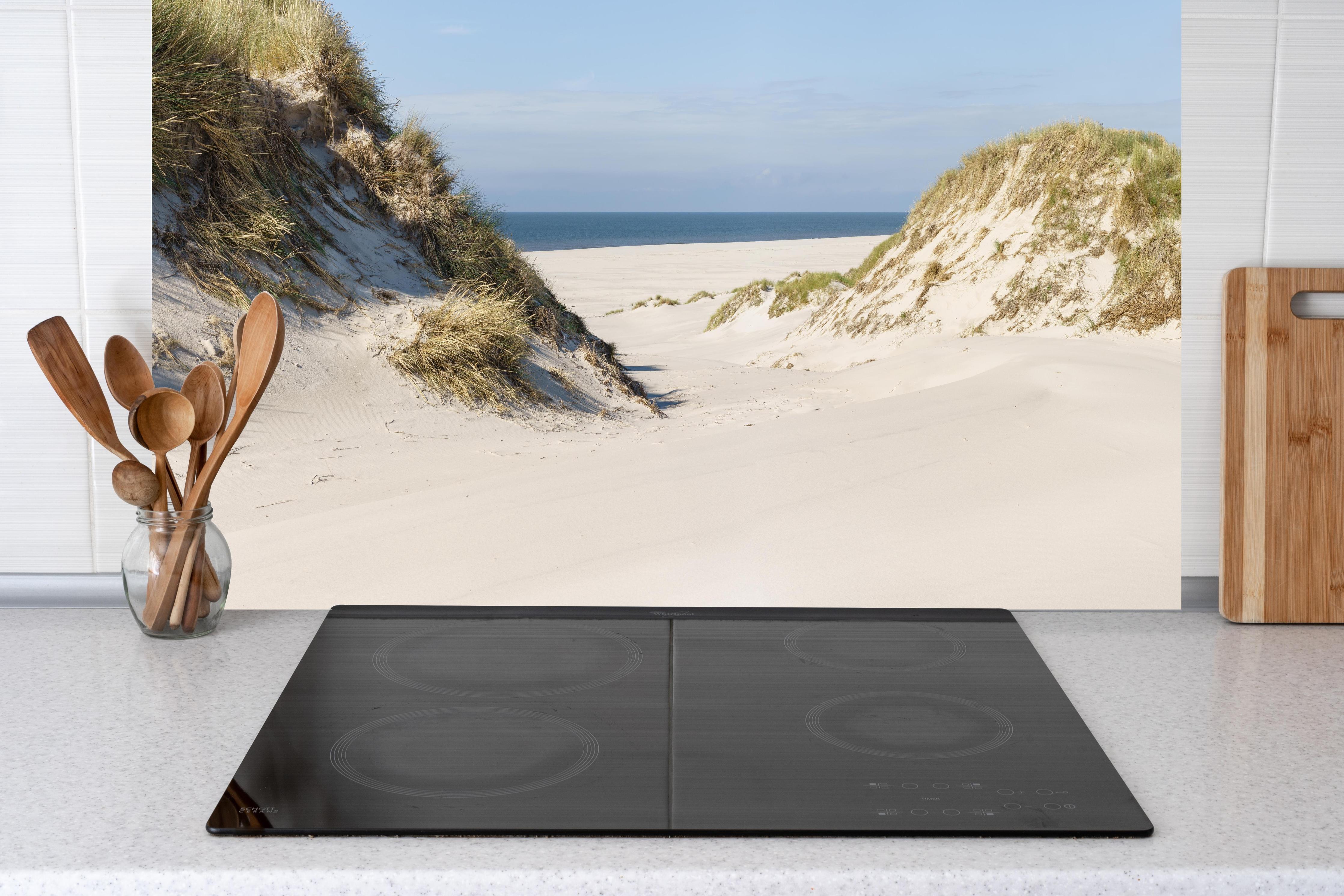 Küche - Traumhafte Sanddüne mit Blick auf das ruhige blaue Meer hinter weißen Hochglanz-Küchenregalen und schwarzem Wasserhahn