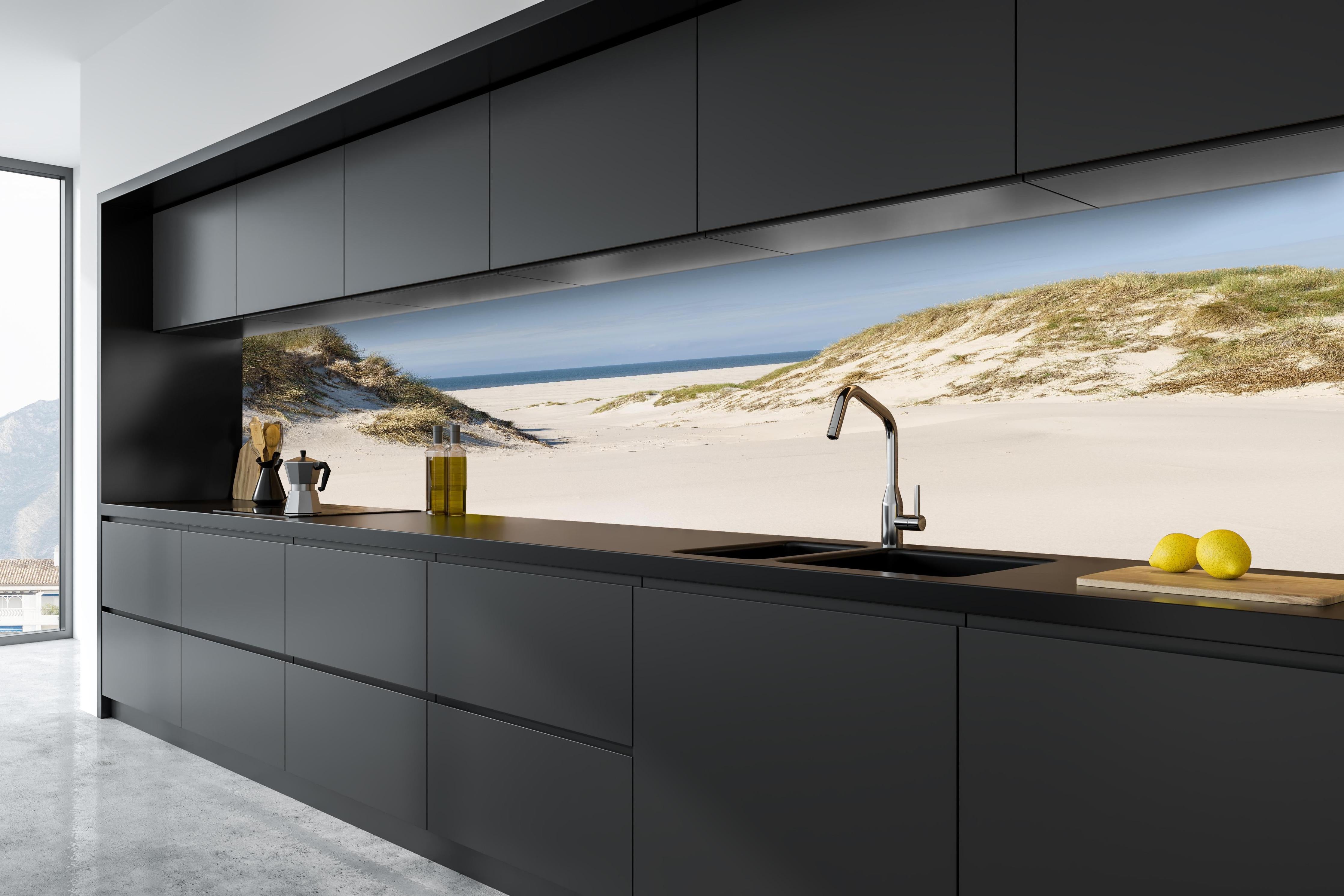 Küche - Traumhafte Sanddüne mit Blick auf das ruhige blaue Meer hinter weißen Hochglanz-Küchenregalen und schwarzem Wasserhahn