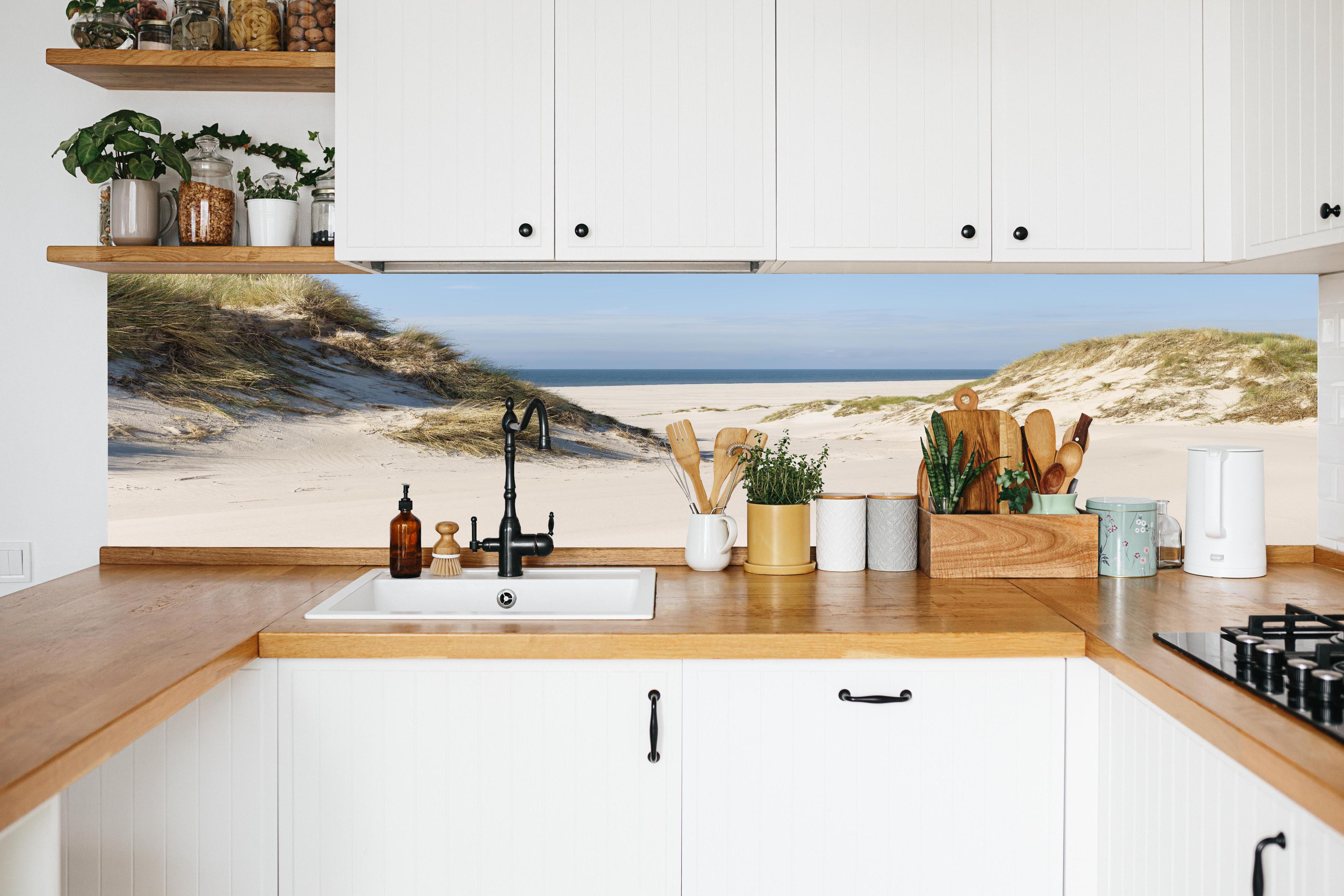 Küche - Traumhafte Sanddüne mit Blick auf das ruhige blaue Meer hinter weißen Hochglanz-Küchenregalen und schwarzem Wasserhahn