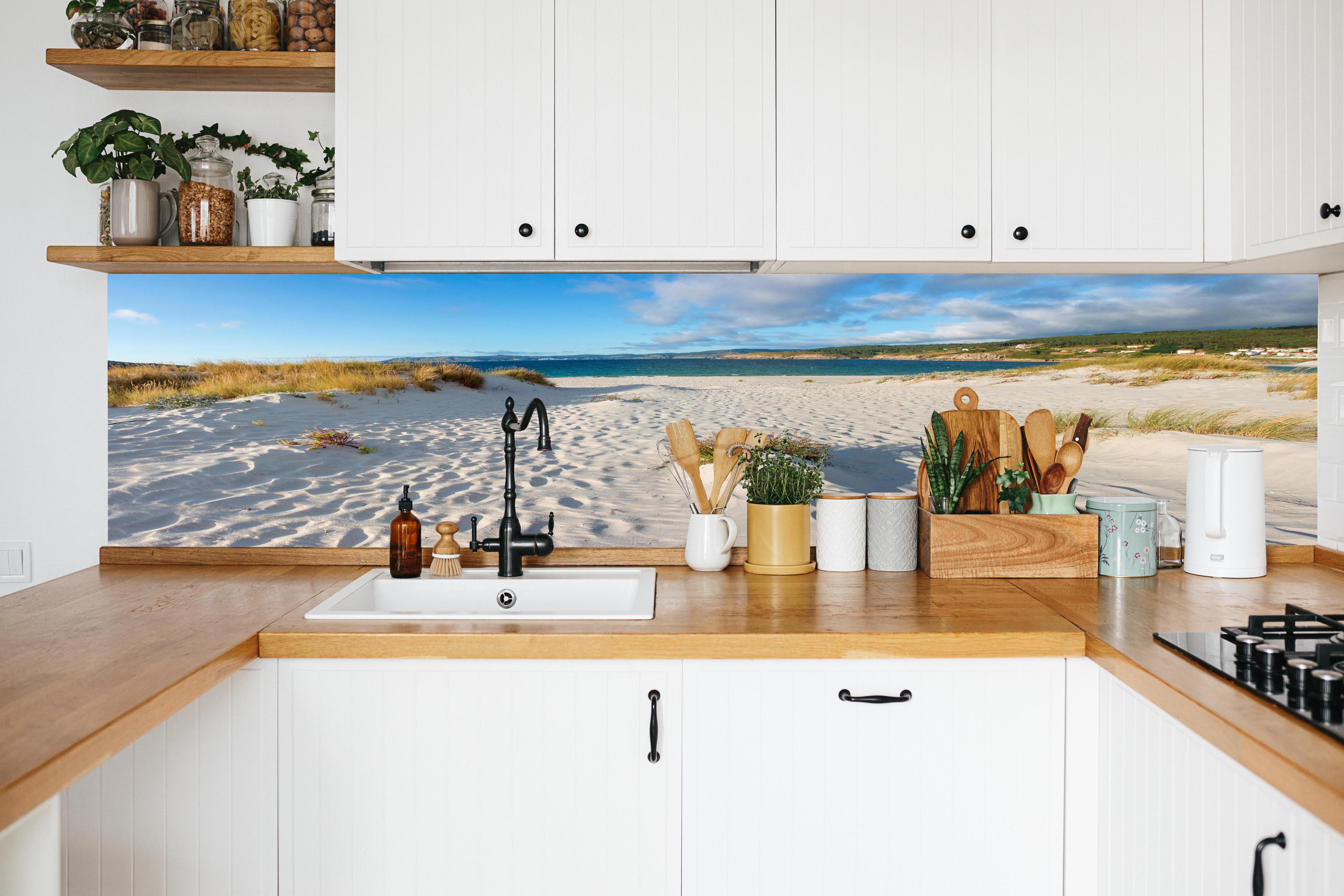 Küche - Traumhafte weiße Sanddünen mit sanftem Blau des Meeres und Himmel hinter weißen Hochglanz-Küchenregalen und schwarzem Wasserhahn