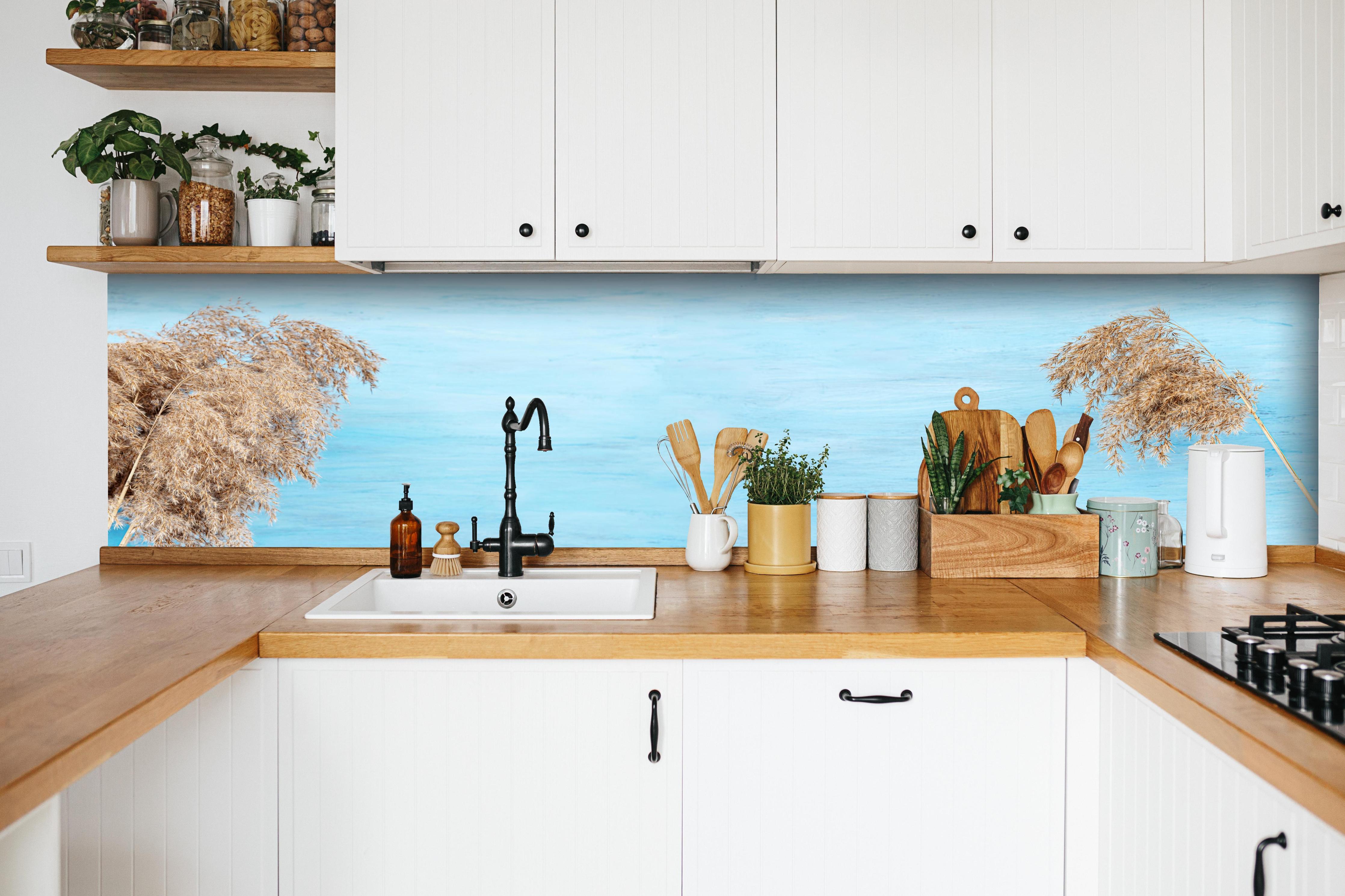 Küche - Trockene Pflanzen über dem Meer hinter weißen Hochglanz-Küchenregalen und schwarzem Wasserhahn
