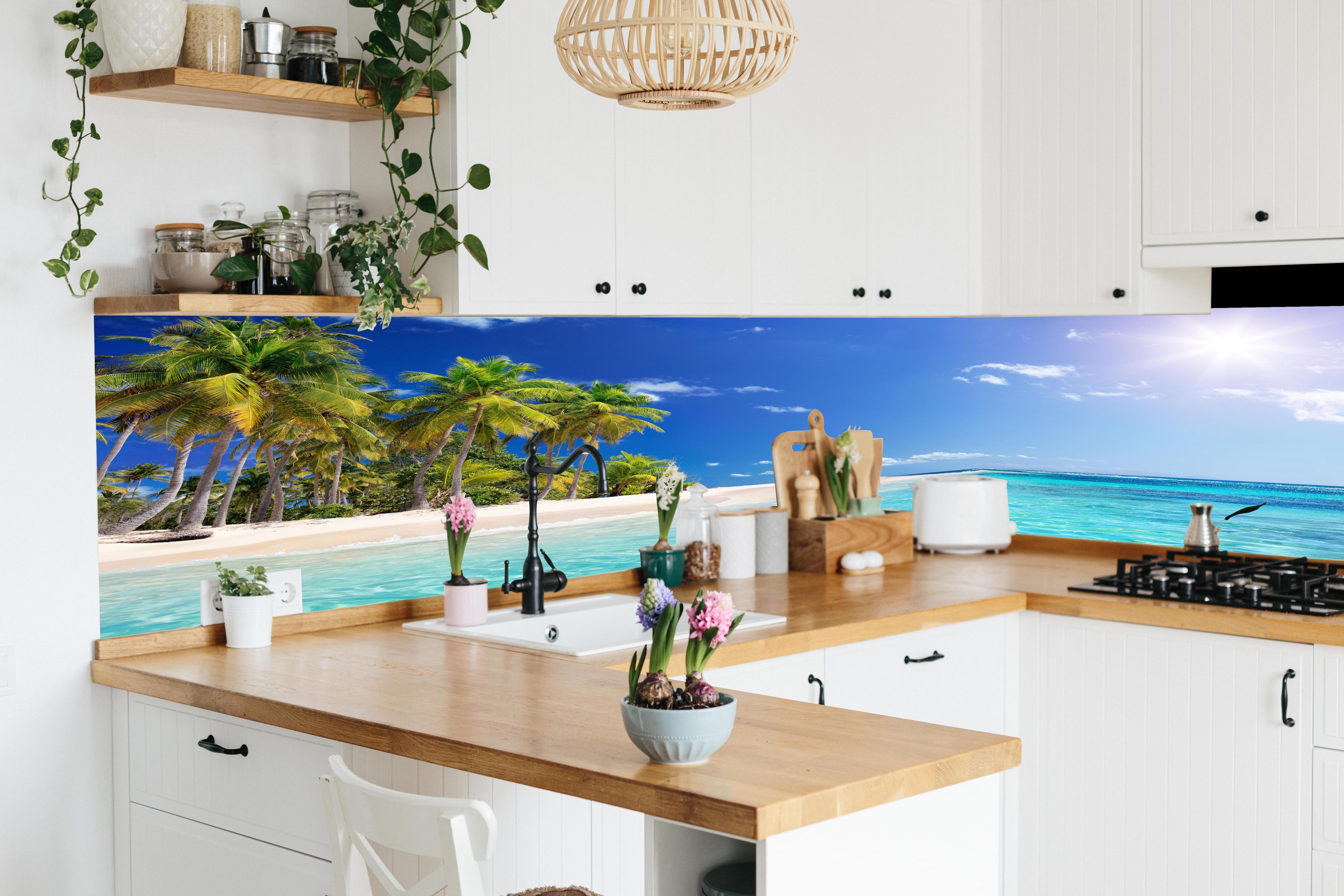 Küche - Tropisches Paradies mit strahlend blauem Himmel und palmenumsäumtem Strand hinter weißen Hochglanz-Küchenregalen und schwarzem Wasserhahn