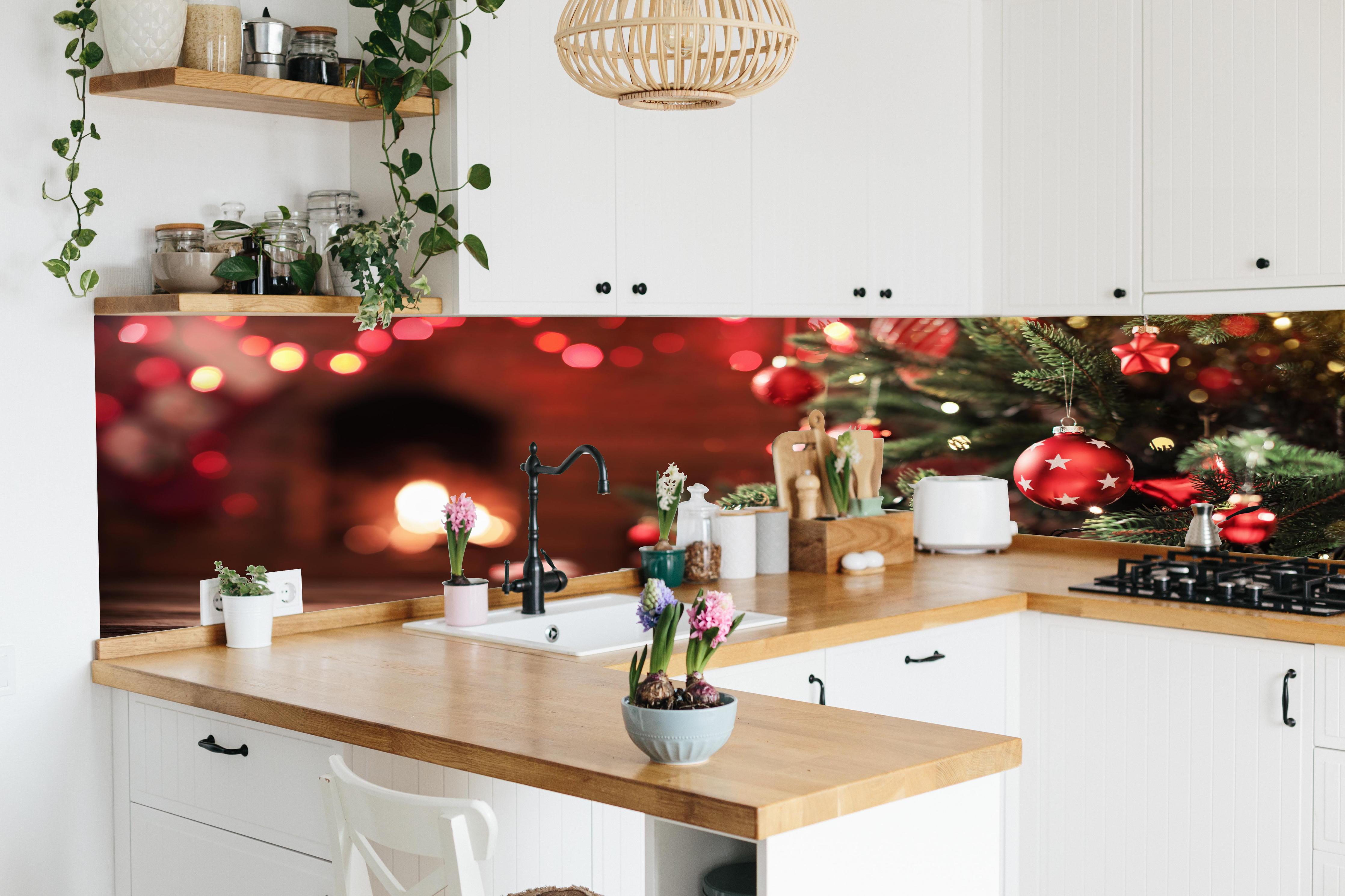 Küche - Weihnachtsbaum mit Dekorationen hinter weißen Hochglanz-Küchenregalen und schwarzem Wasserhahn